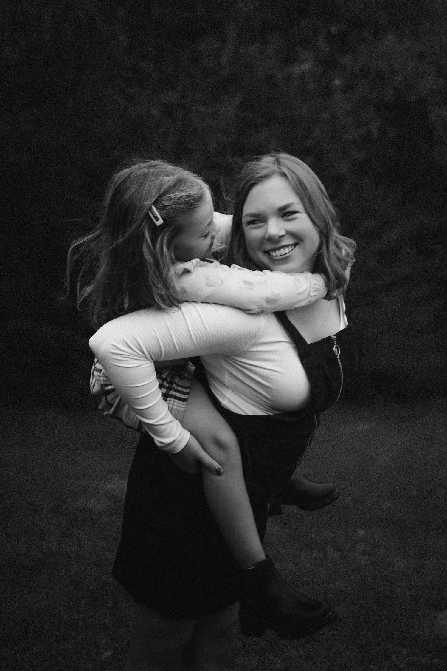A sequence of black and white photos showing joyful embraces and playful interactions outdoors.