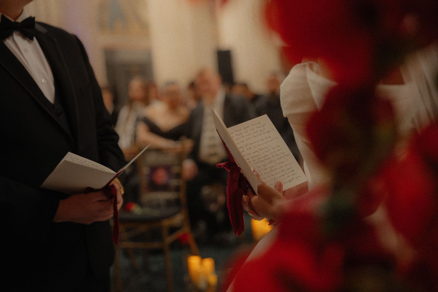 Officiant and guest reading from booklets during an indoor wedding ceremony.
