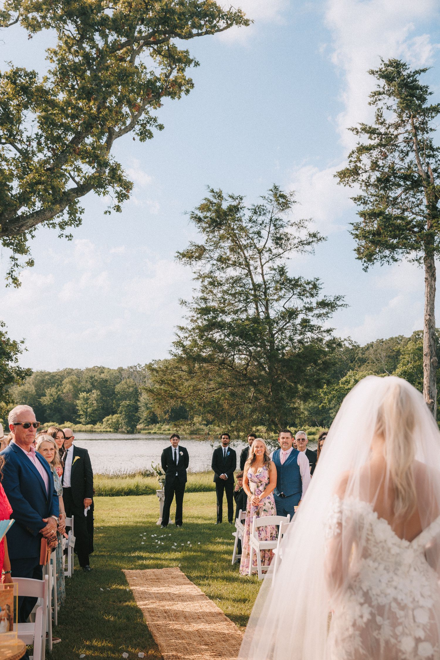 Outdoor wedding ceremony setup with white chairs and natural landscape backdrop.