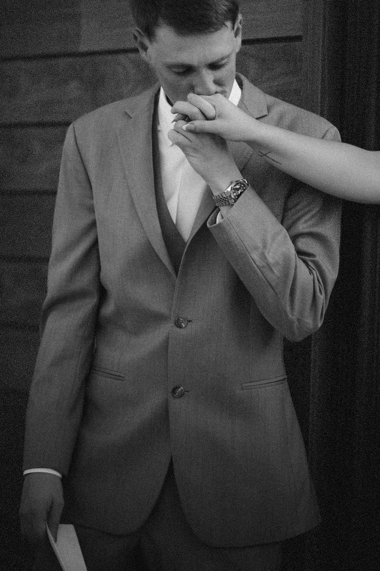 A black and white sequence of images shows someone in a formal suit wiping their face and nose.