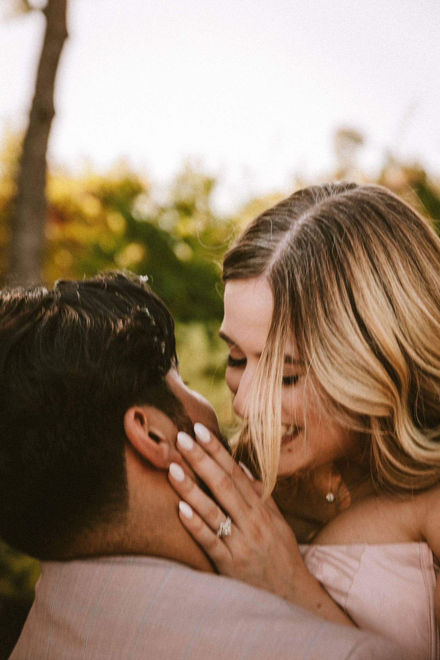 An intimate close-up of a couple sharing a tender moment outdoors in warm evening light.