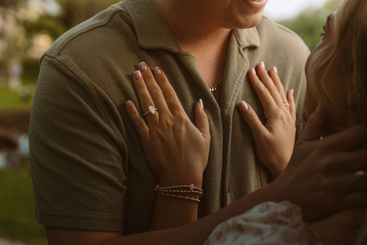 Close-up of a woman showing her engagement ring with hands placed on a mans chest.