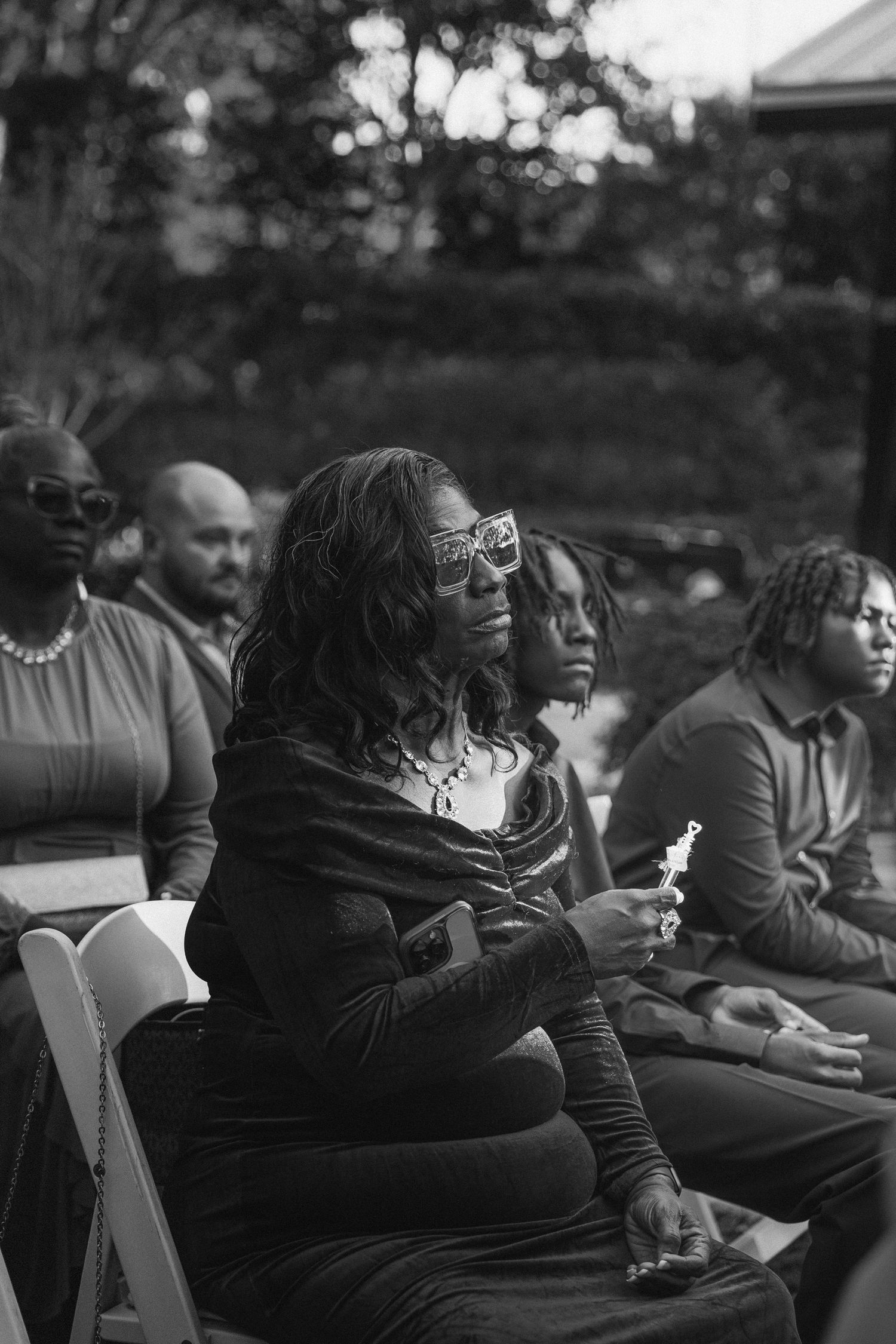 Black and white photo of wedding guests seated outdoors during fall ceremony.