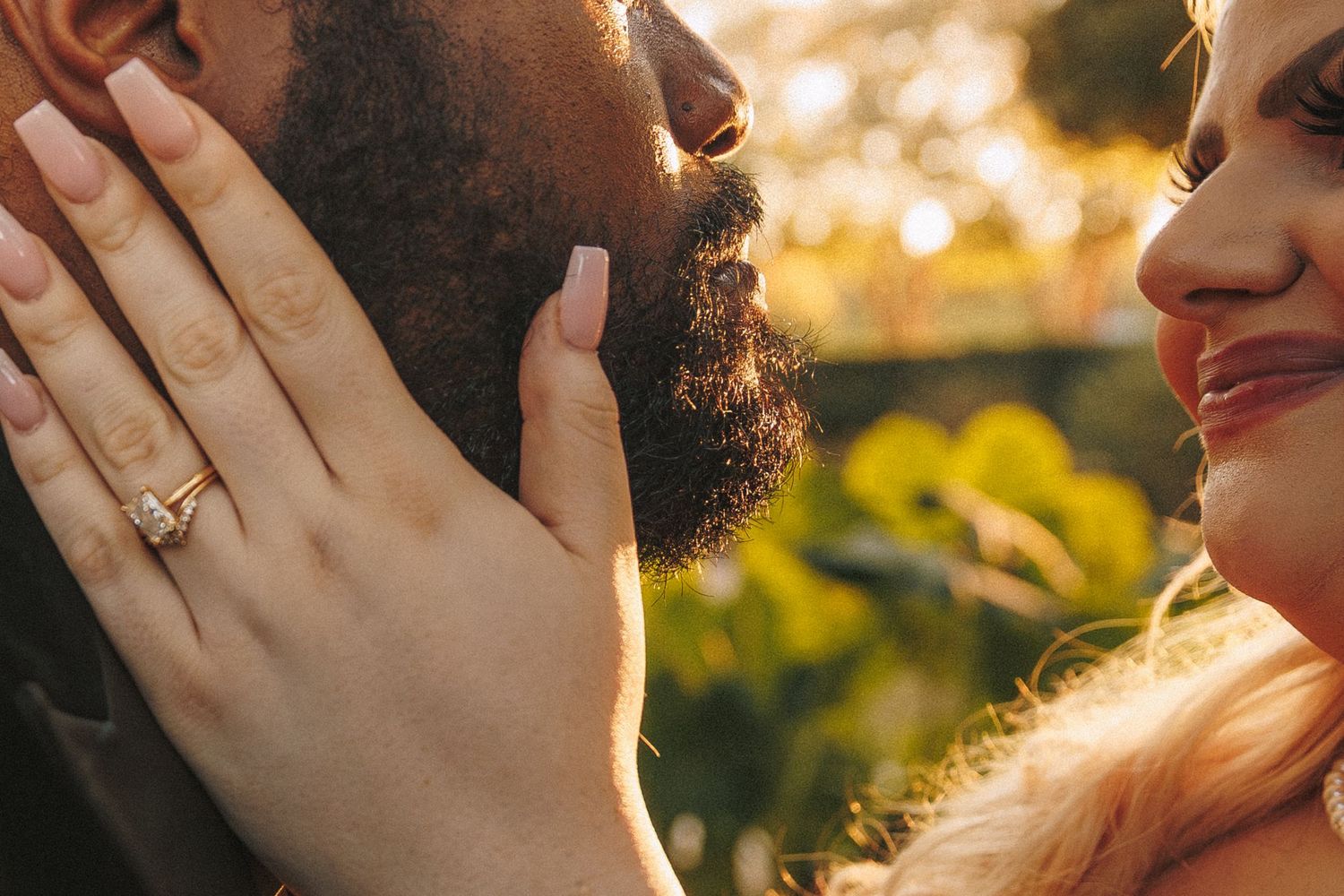 Close-up of bride and groom almost kissing with diamond engagement ring visible.