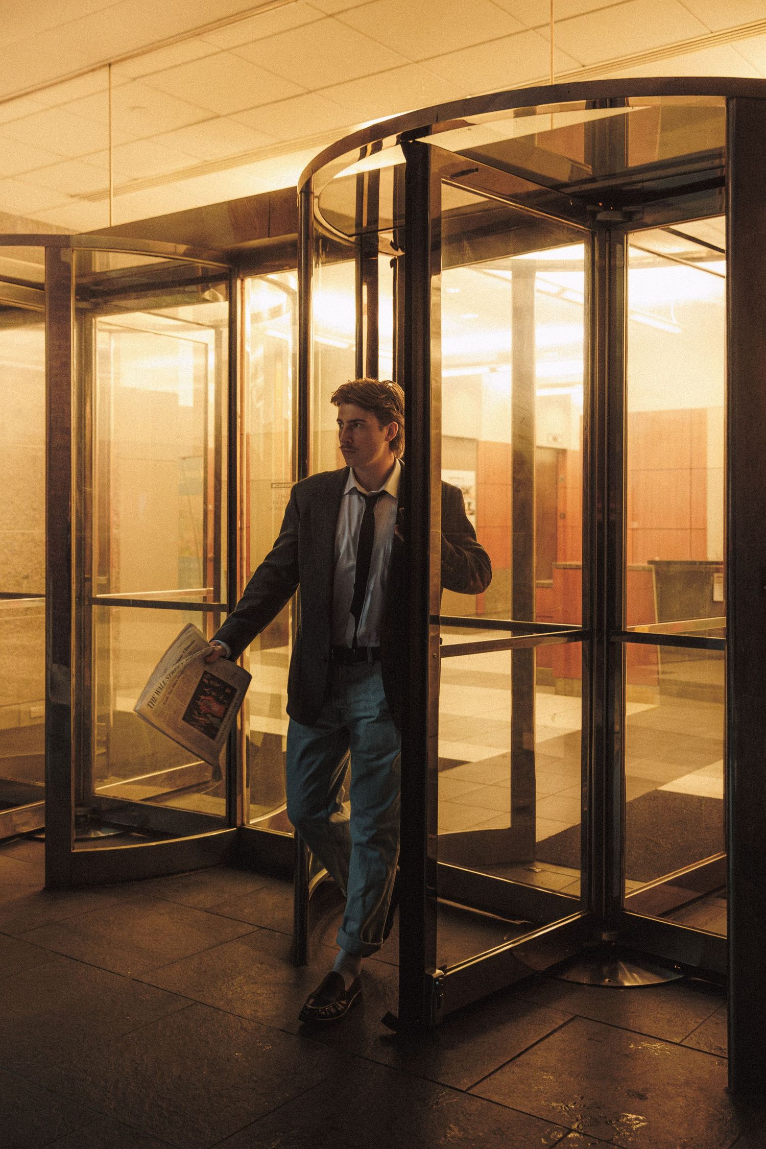 A sequence showing a person in business attire moving through a revolving door in an office building lobby.