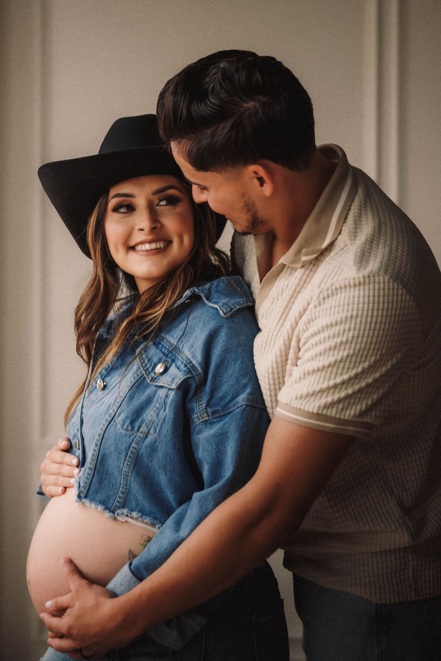 A couple shares intimate moments in a denim and casual wear maternity photo series showing a growing baby bump.