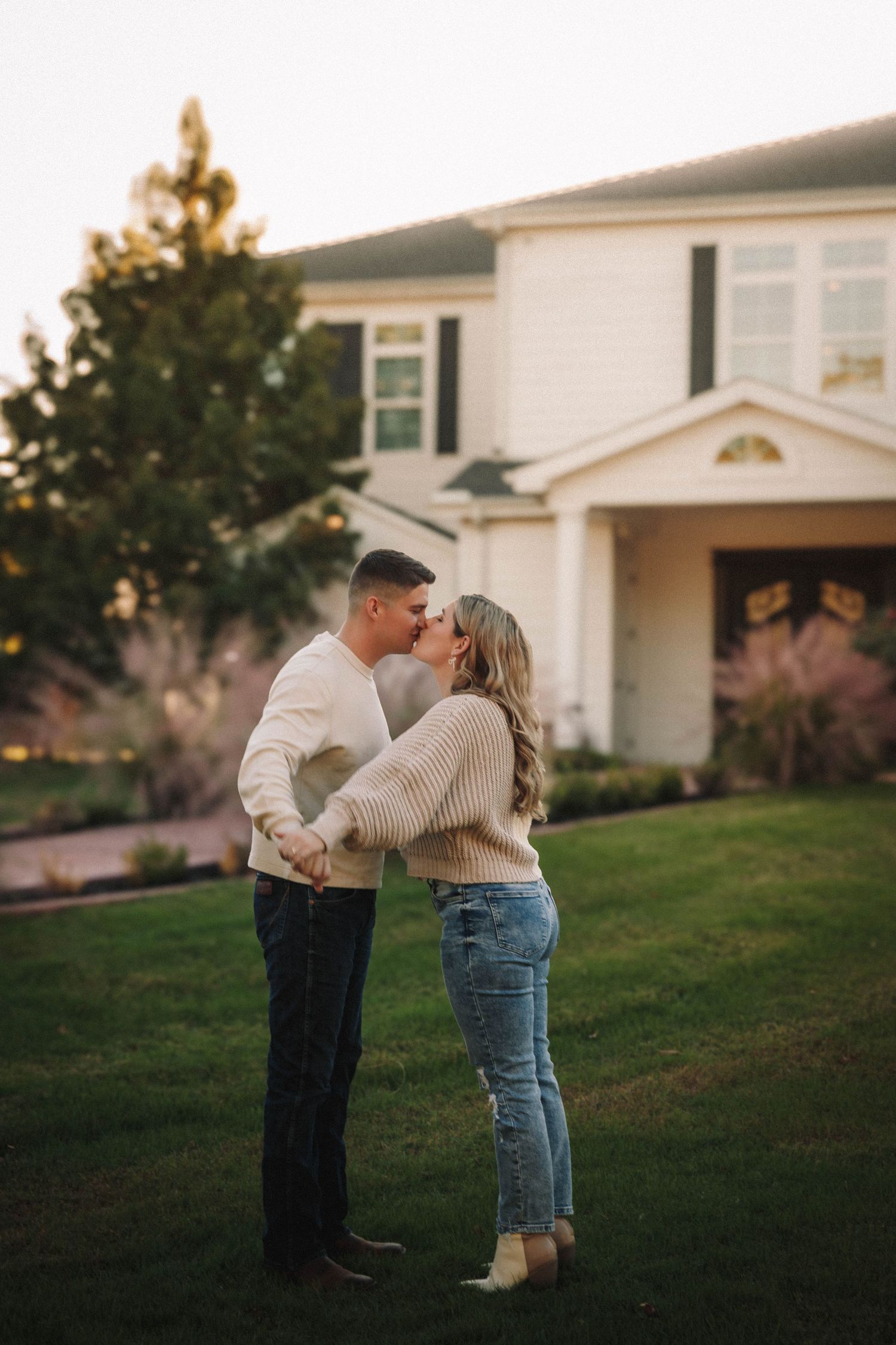 Romantic sequence of a couple dancing together on a grassy lawn at sunset.