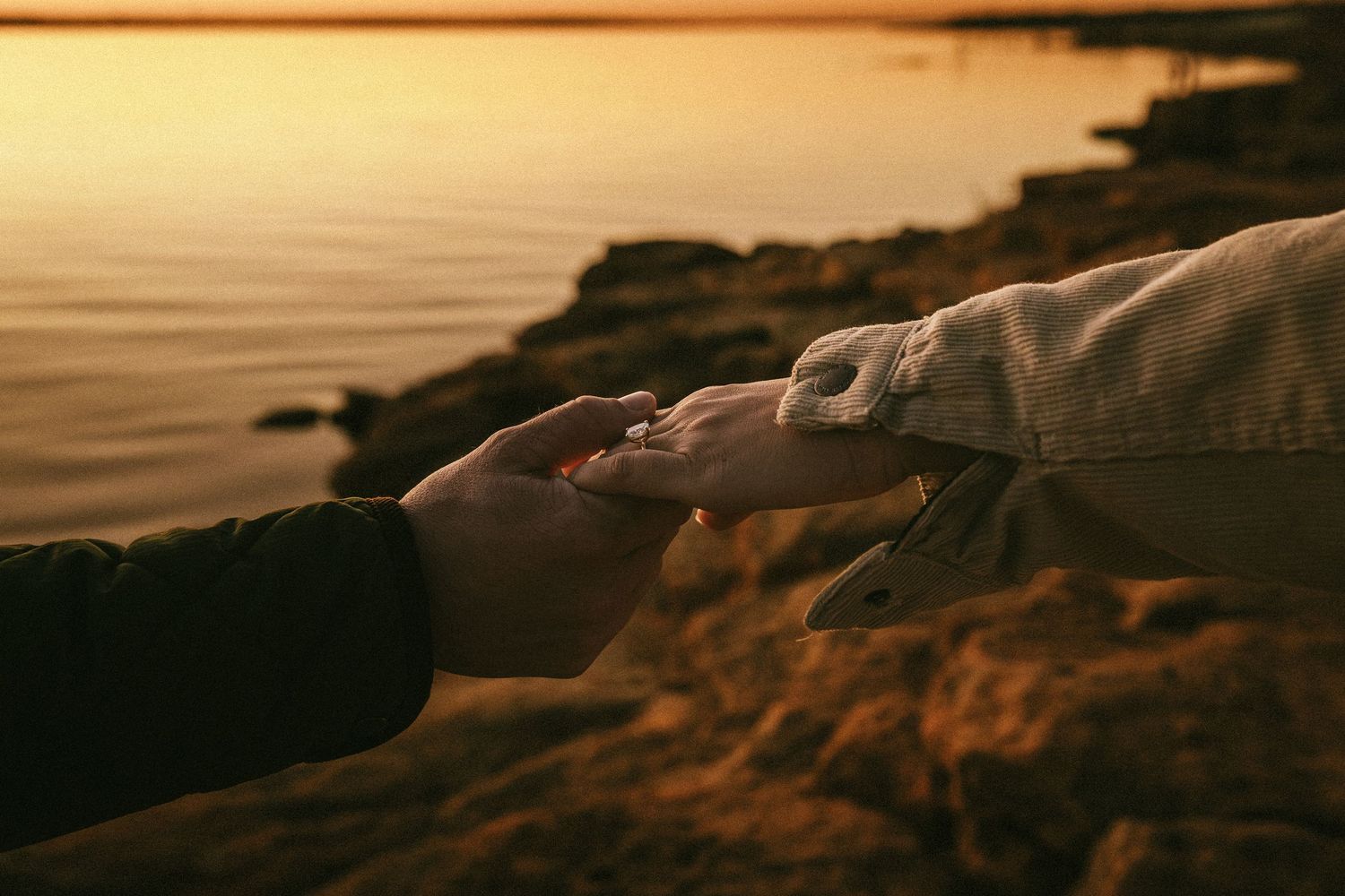 Silhouetted couple shares an intimate moment against a dramatic coastal sunset backdrop.