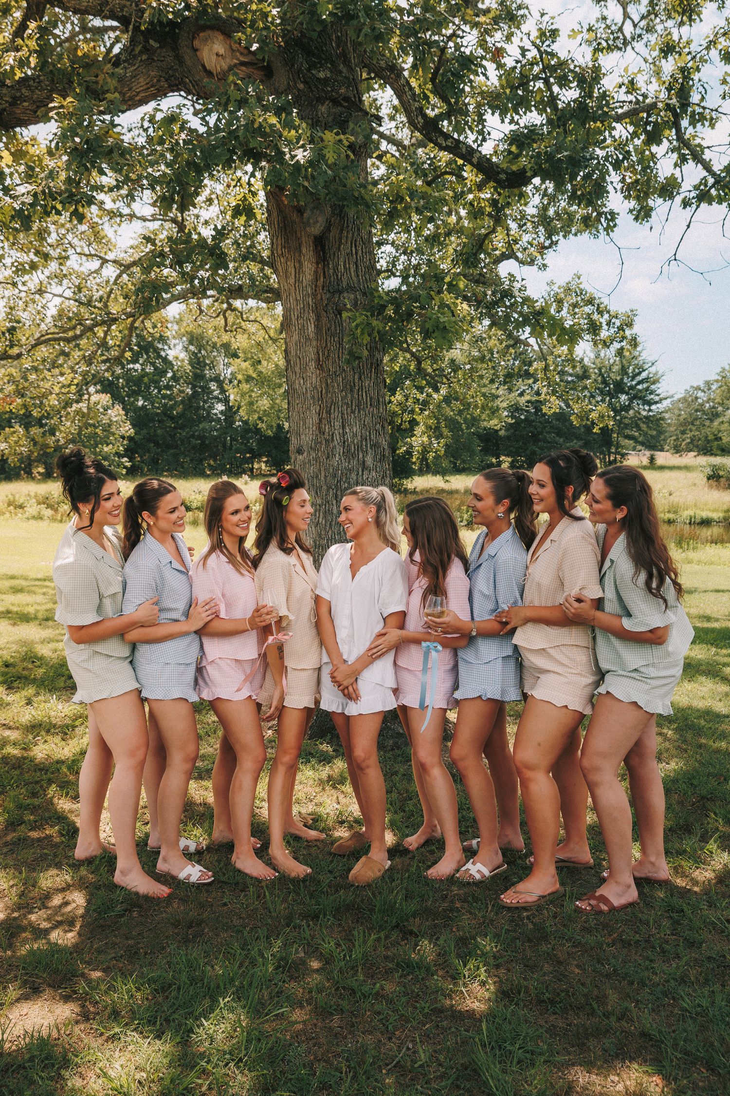 Group photo outdoors showing casual attire and matching outfits under a large tree.