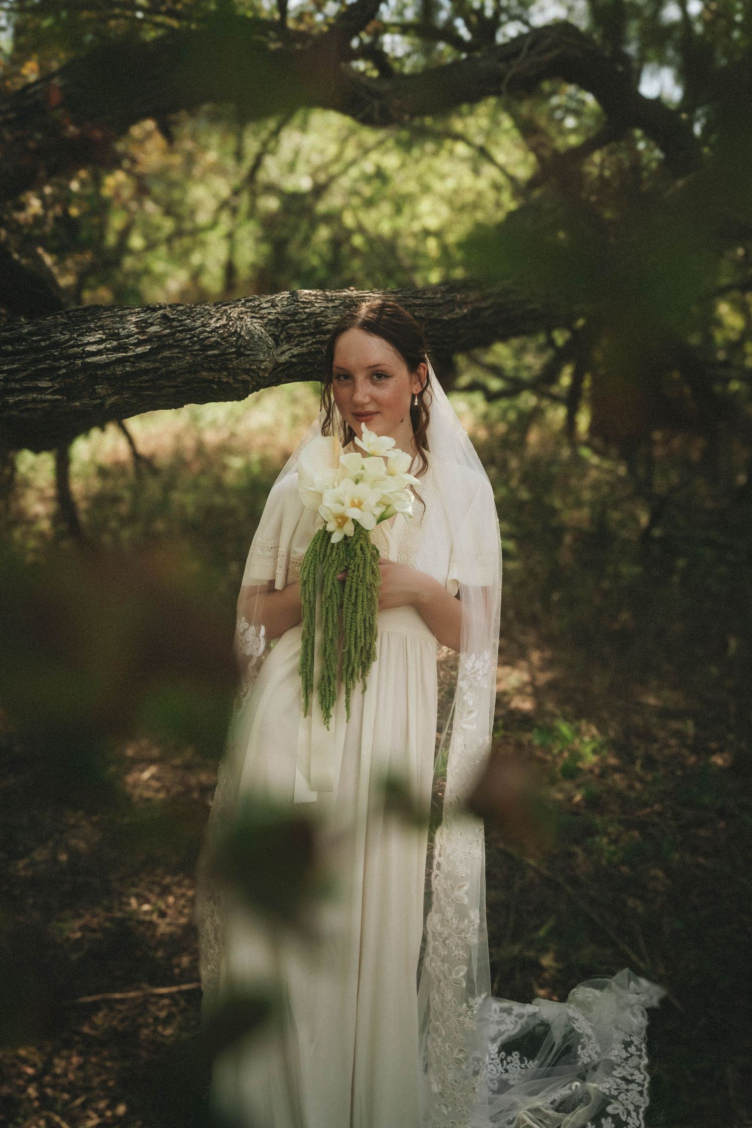 Ethereal woodland maternity photoshoot featuring a dreamy white lace dress against a natural forest backdrop.
