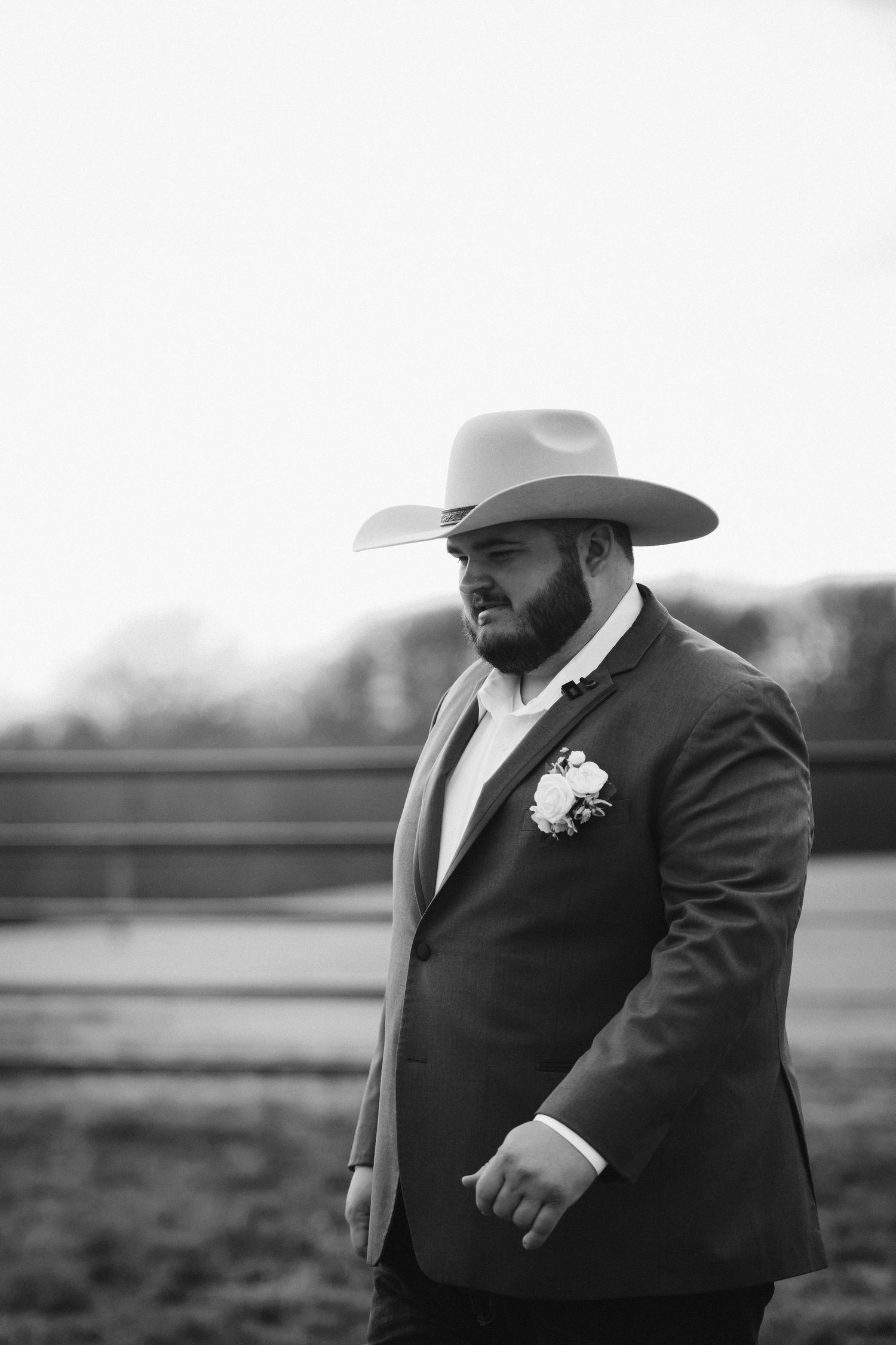 A person in a suit and cowboy hat poses dramatically in a black and white outdoor portrait series.