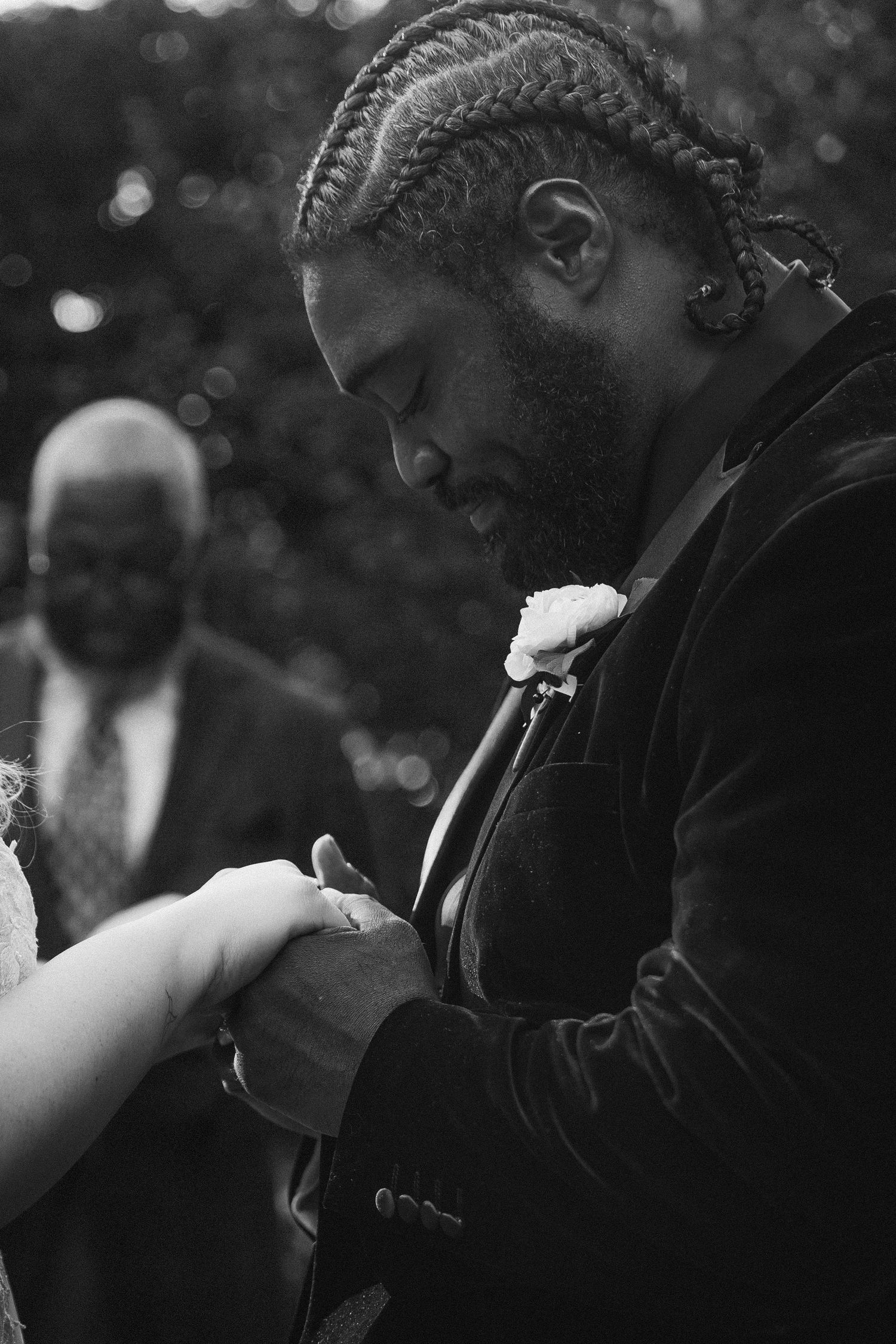 Black and white photo of groom placing ring on bride's hand during wedding ceremony.