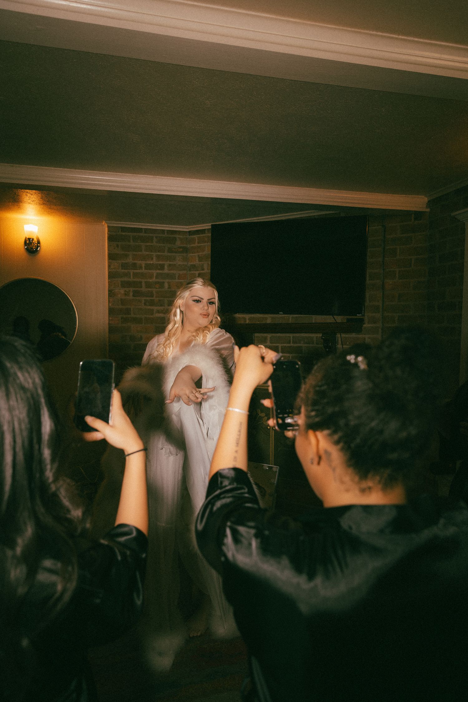 Blonde singer in silver gown performing with microphone at elegant indoor wedding reception.