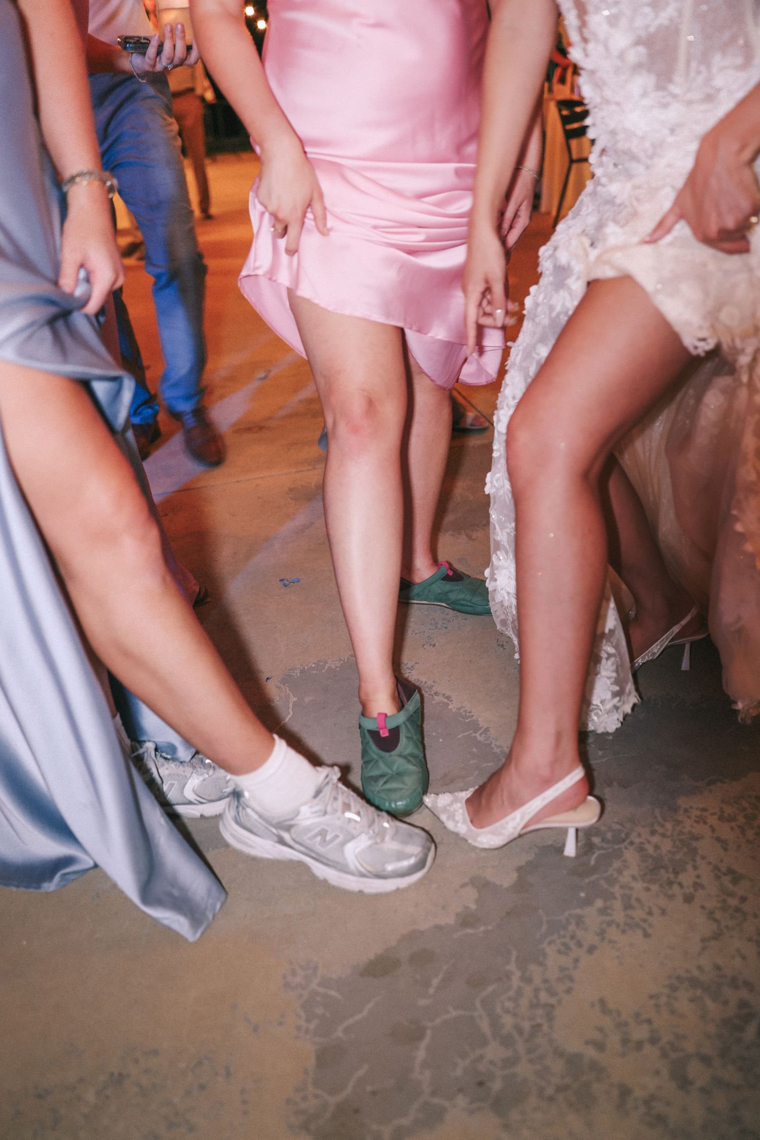A closeup of dancers' feet and legs in formal wear on a dance floor.