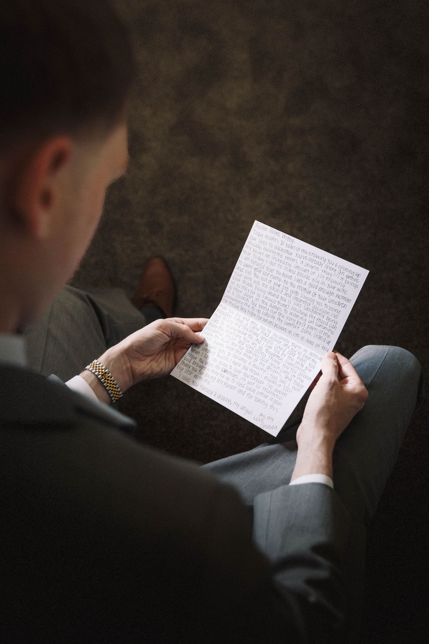 A close-up sequence showing hands holding and reading a handwritten letter on white paper against a dark background.