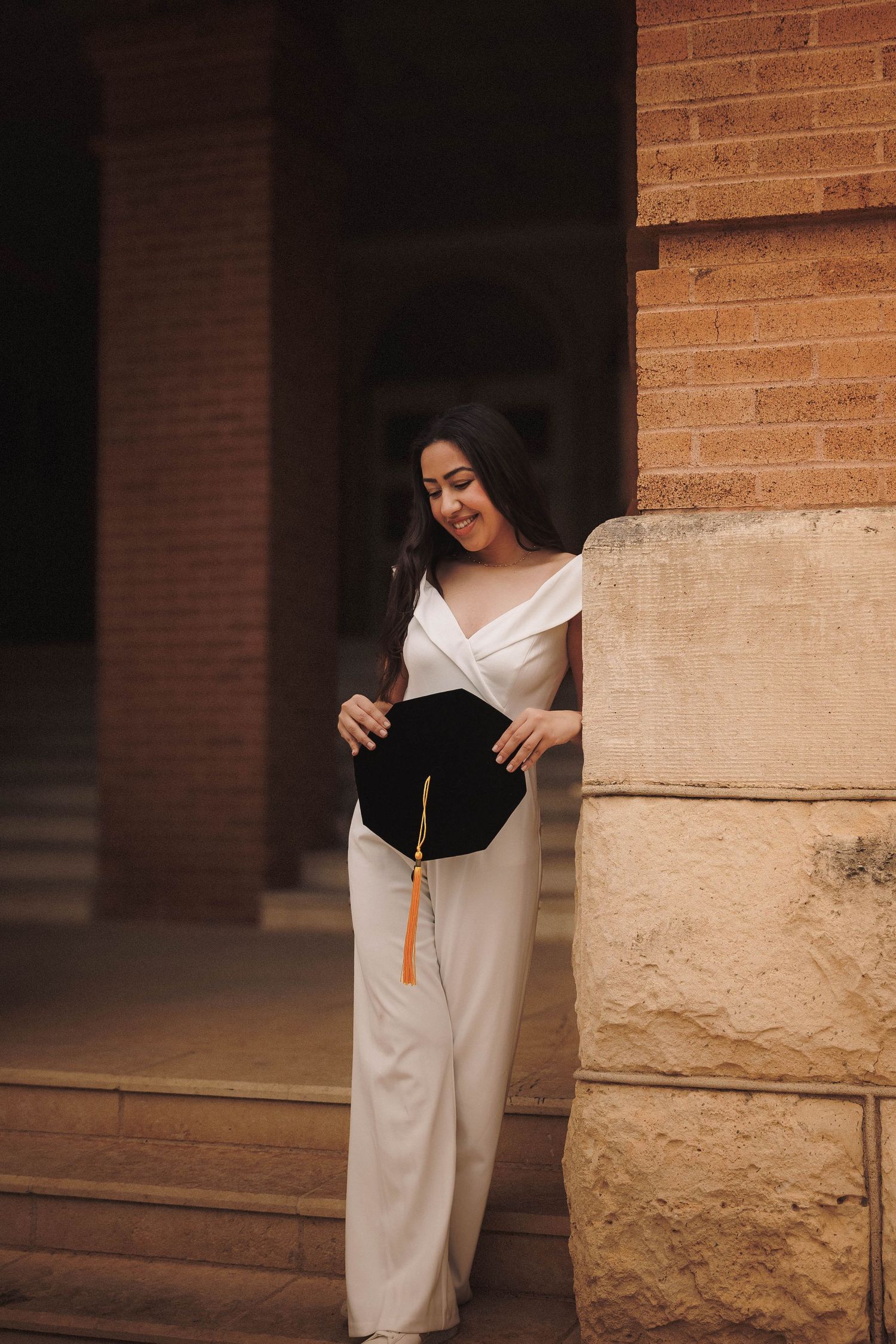 Someone in a white dress poses reading a book against a brick wall in a progression of different graceful poses.