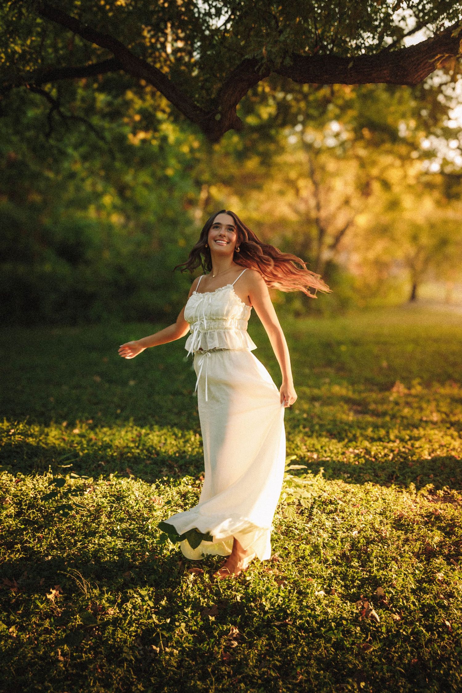A woman in a flowing white dress runs through a sunlit field of wildflowers at golden hour.