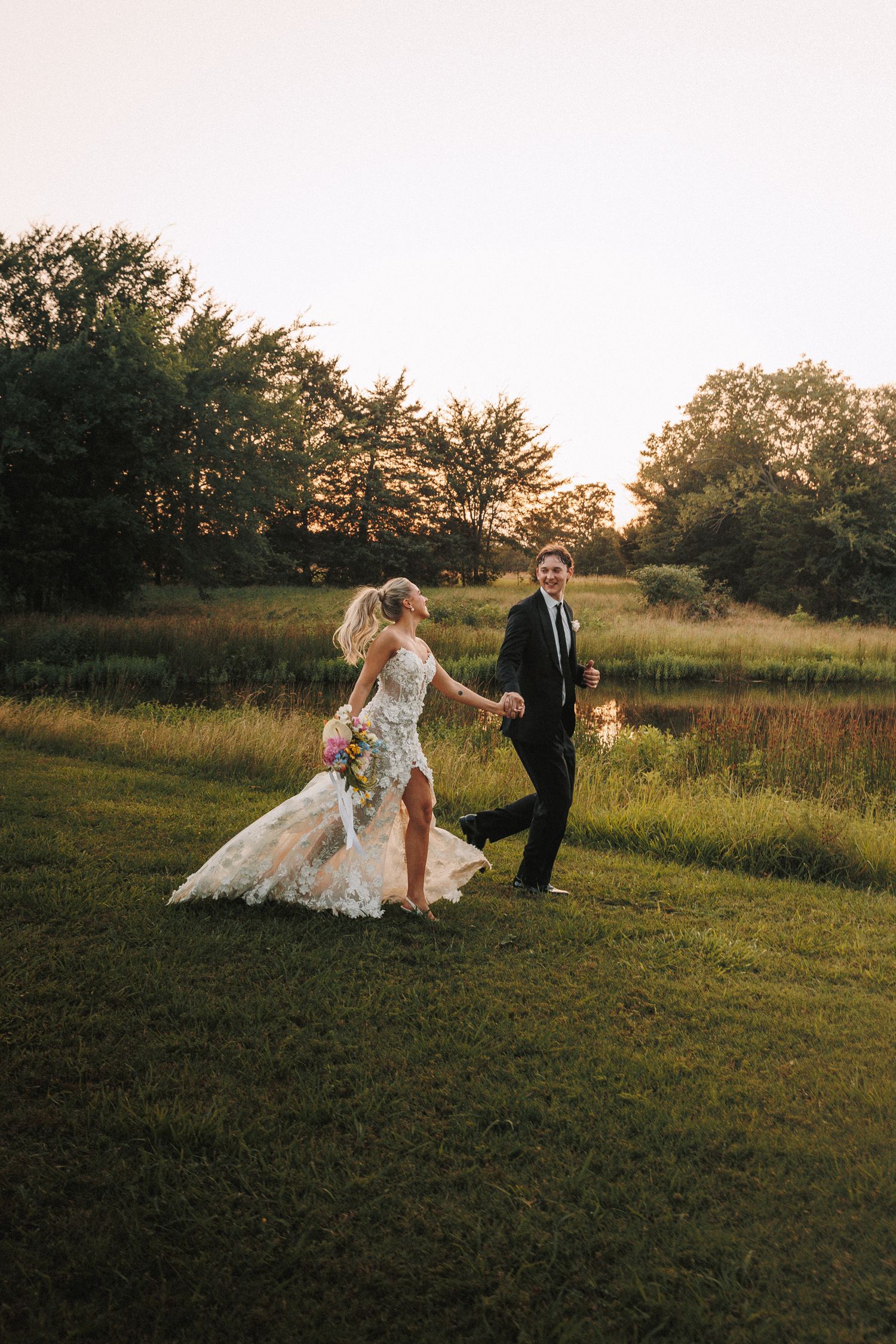 Couple dancing in a grassy field during golden hour at their wedding.