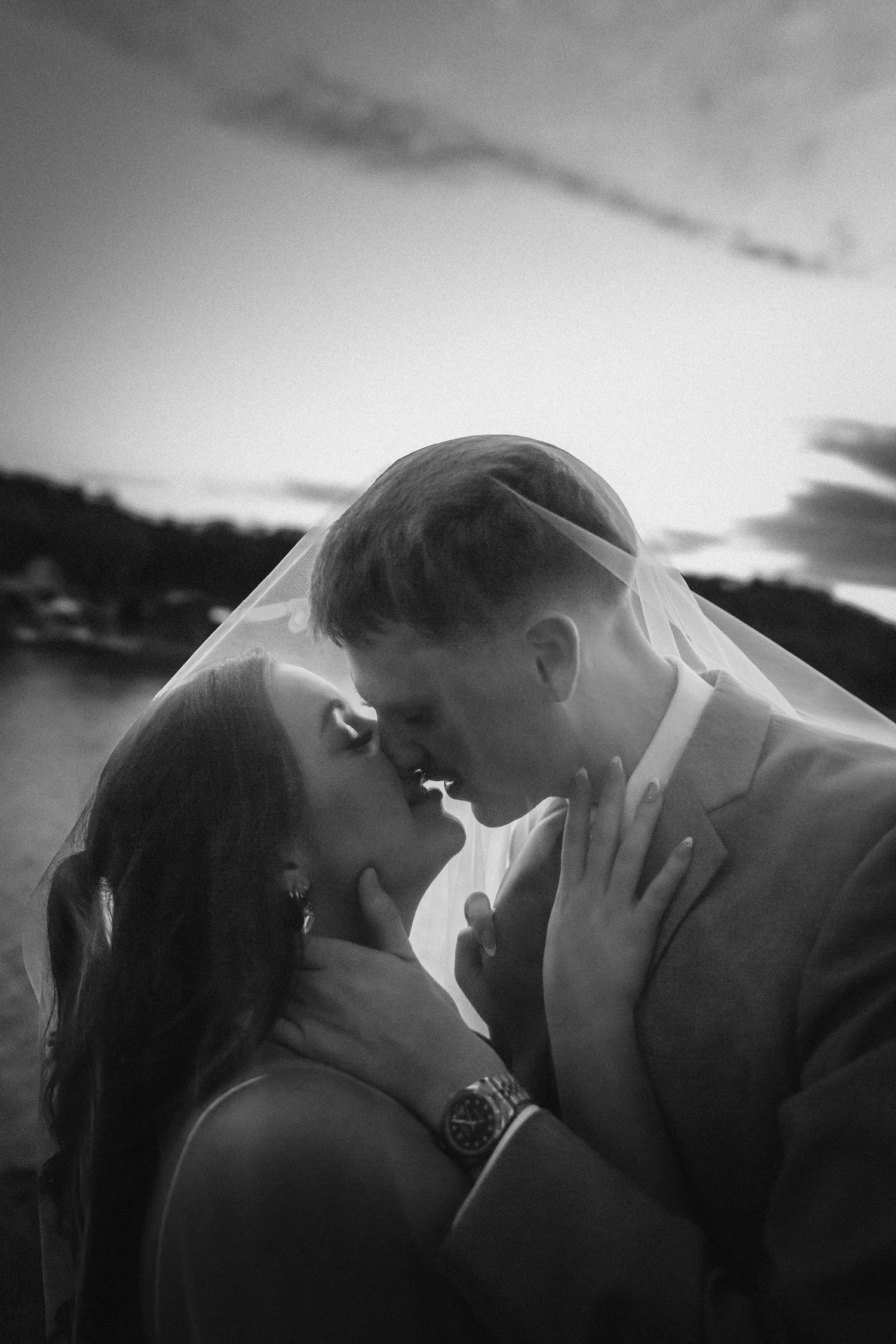 A romantic black and white photo sequence showing a couple sharing an intimate kiss at sunset against a dramatic sky.
