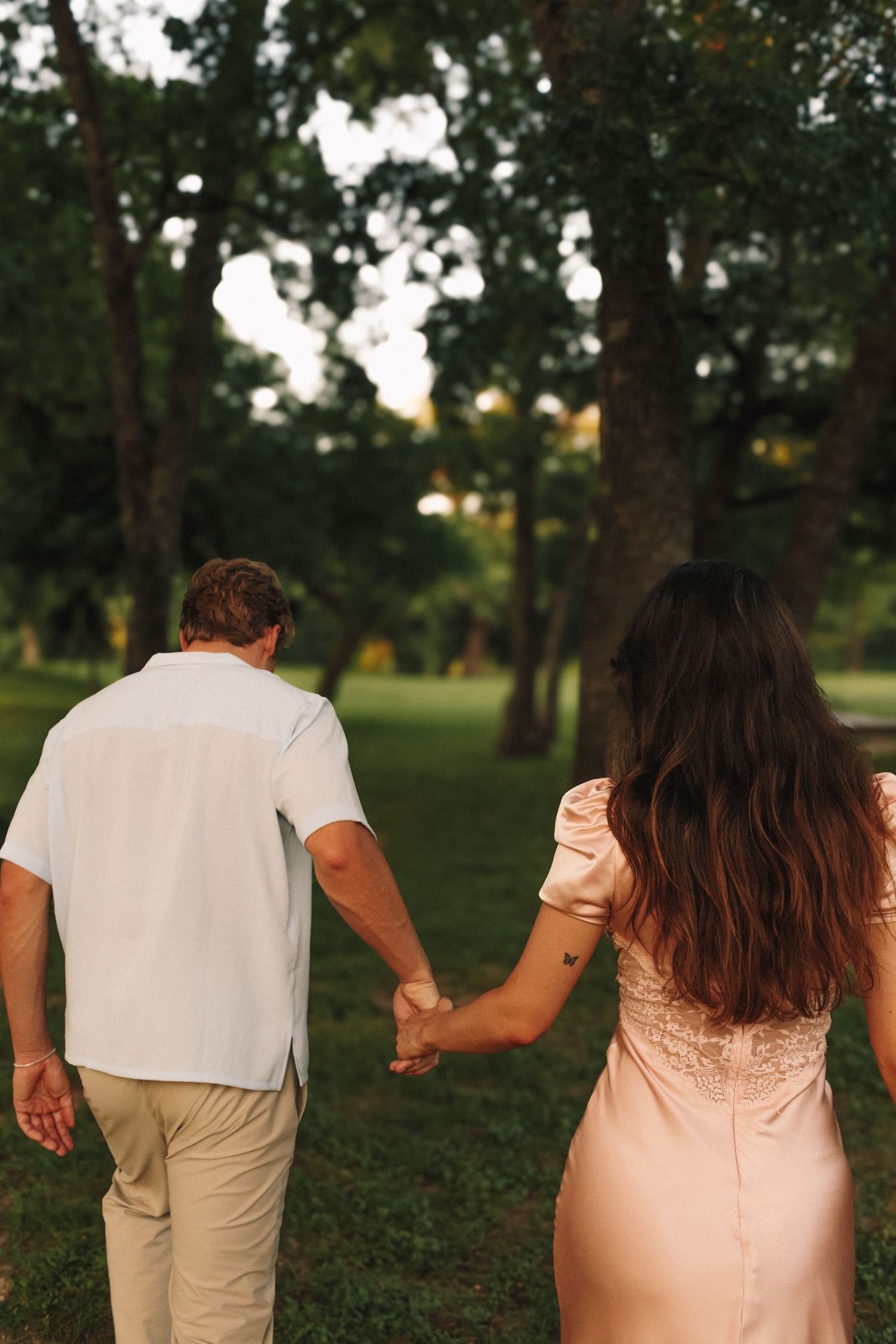 A series of images showing two people walking hand in hand through a park at sunset with trees in the background.