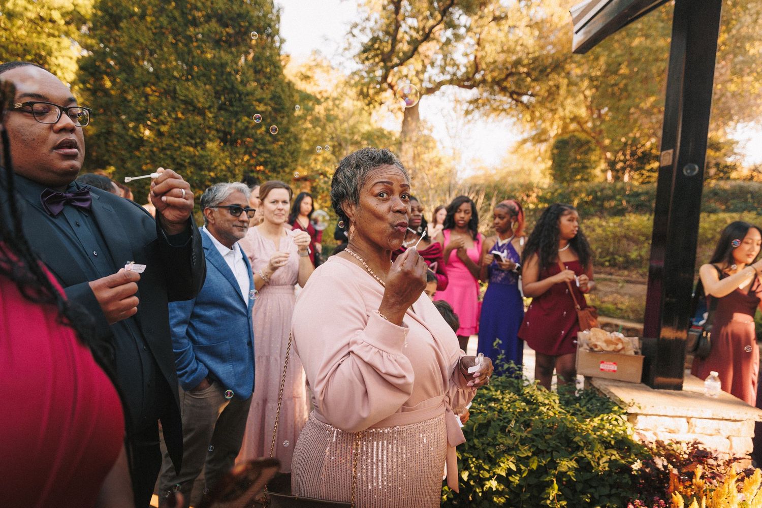 Wedding guests react emotionally during an outdoor ceremony surrounded by autumn foliage.