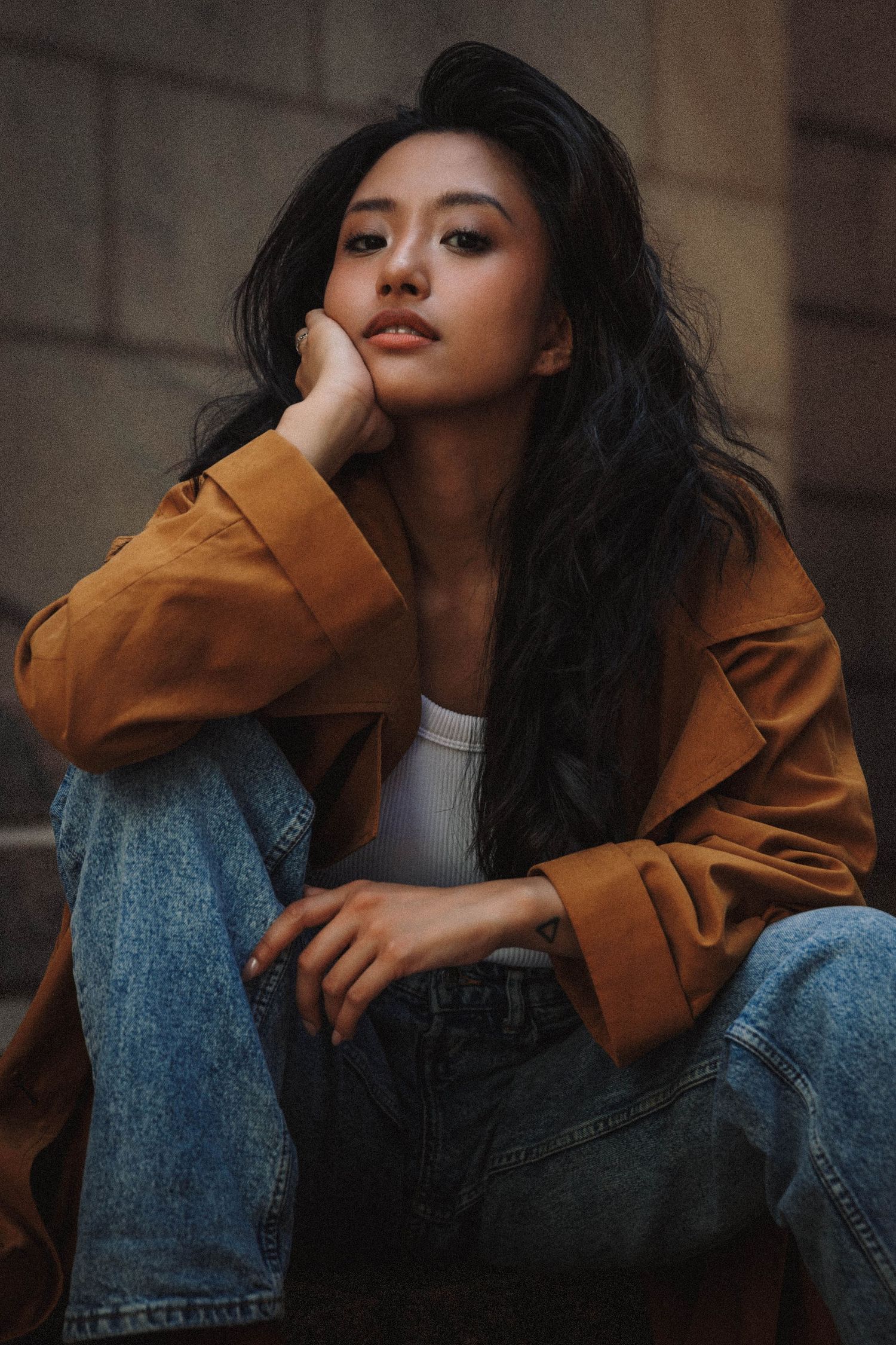A series of artistic portraits showing someone in blue jeans and tan jacket against a neutral background.