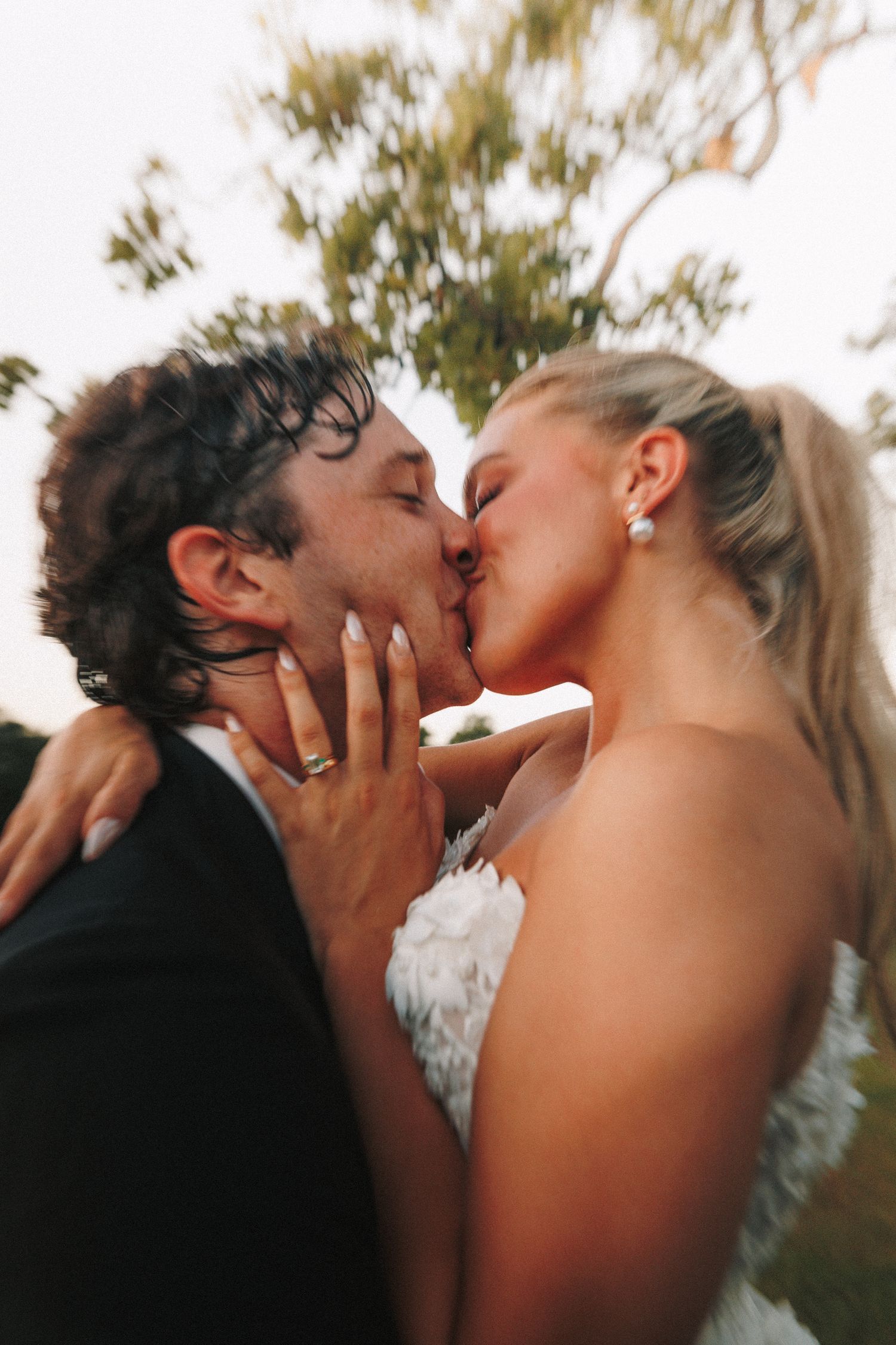 A romantic candid moment between newlyweds during an outdoor sunset photo session.