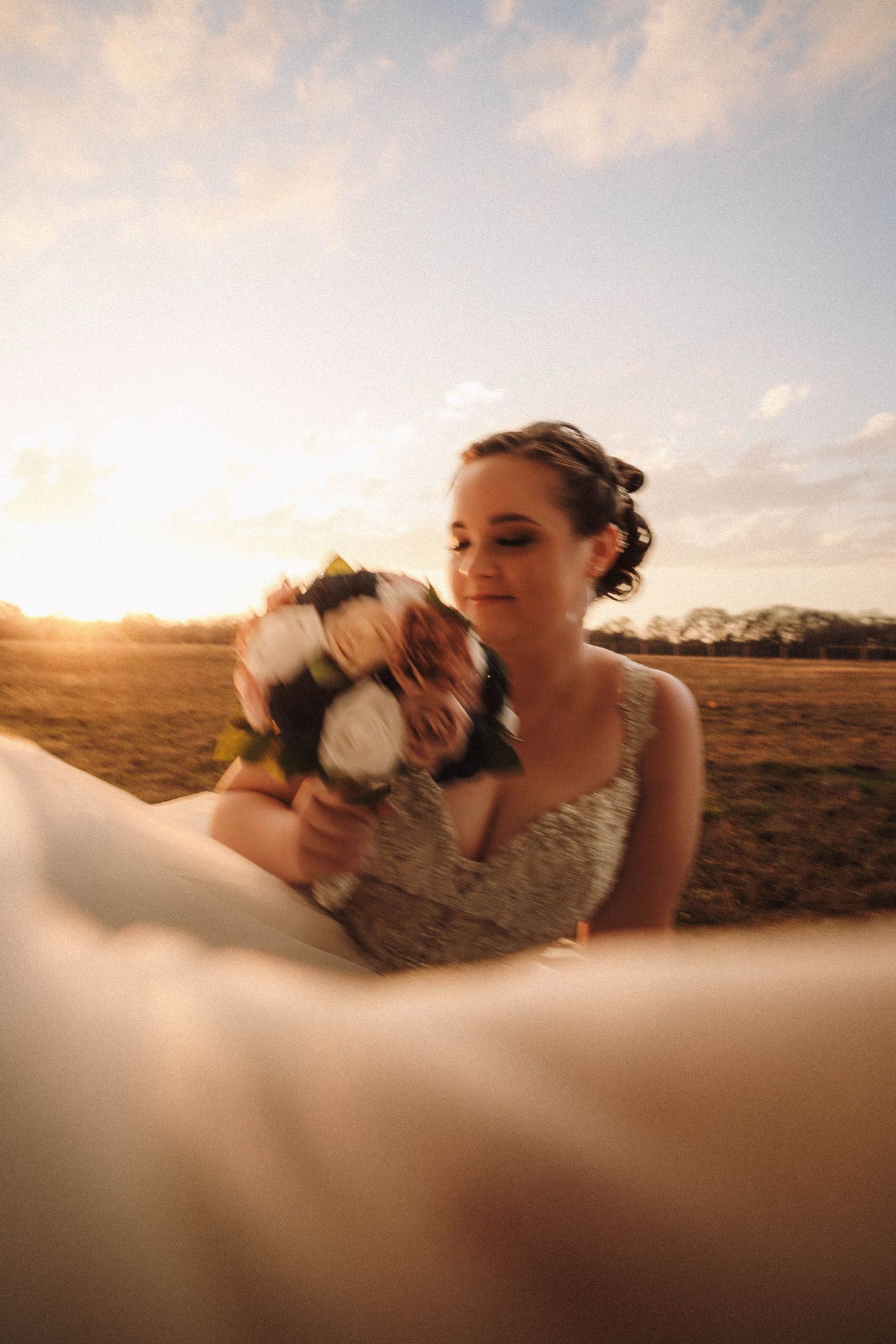 Dog gives affectionate kisses during a sunset photoshoot in an open field with mountains in the background.