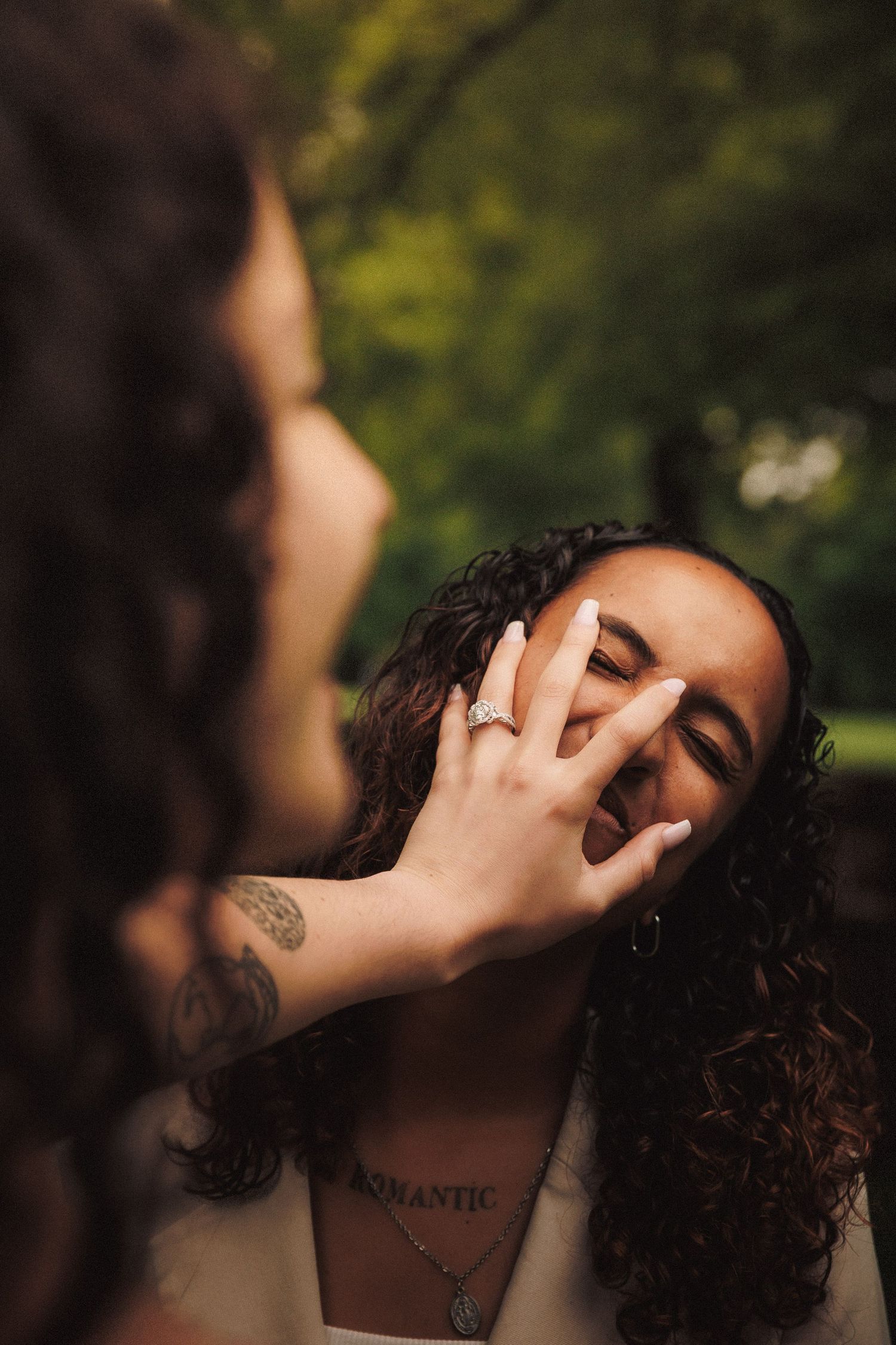 A person with curly dark hair covers their face with their hand in a series of soft natural light portraits.