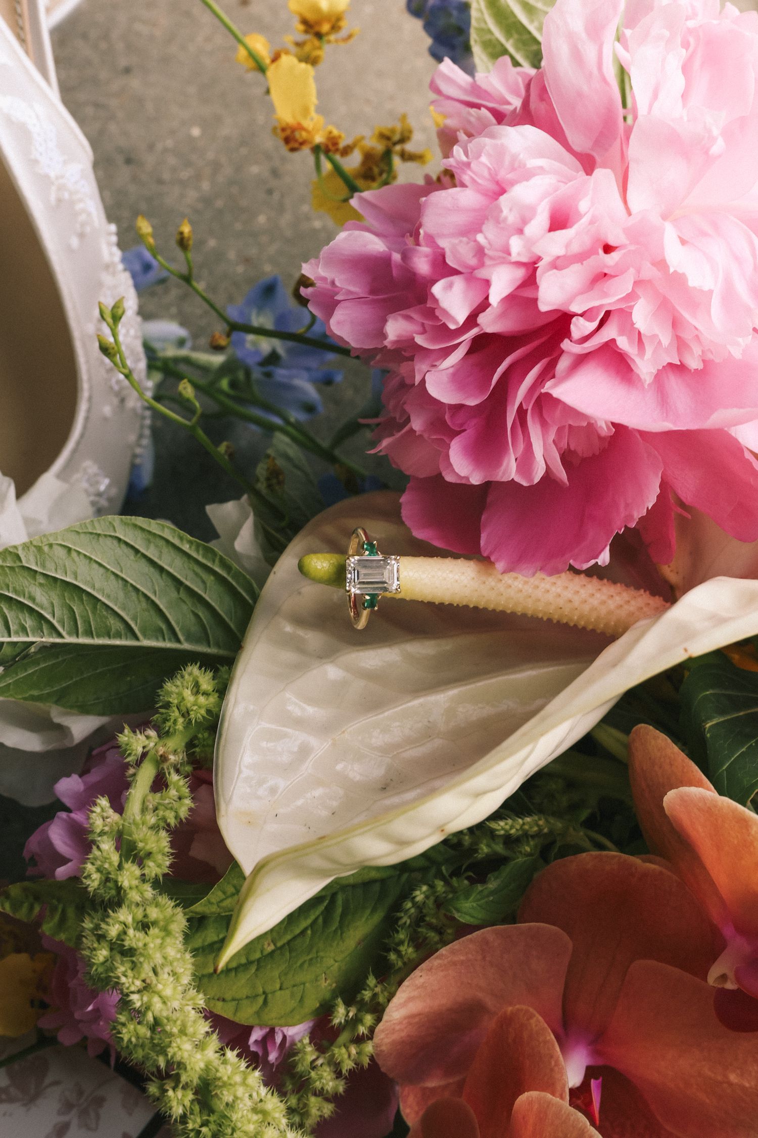 Close up of a pink peony flower arrangement with white calla lilies and greenery on display.