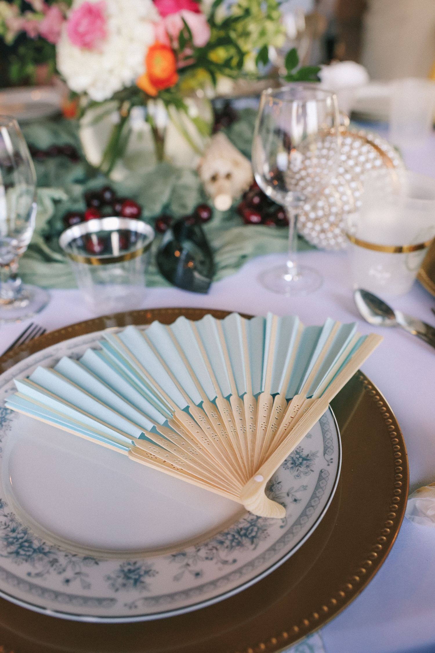 Elegant place settings feature light blue paper fans on delicate china with floral details.