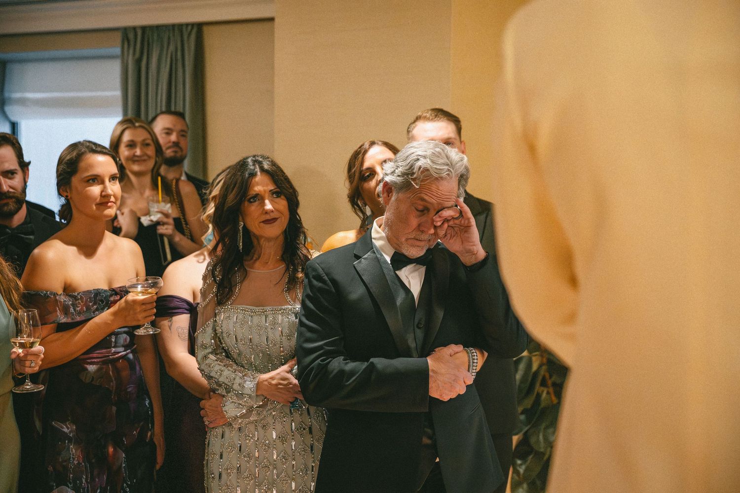 Emotional wedding guests wipe tears watching the grooms during a heartfelt wedding ceremony.