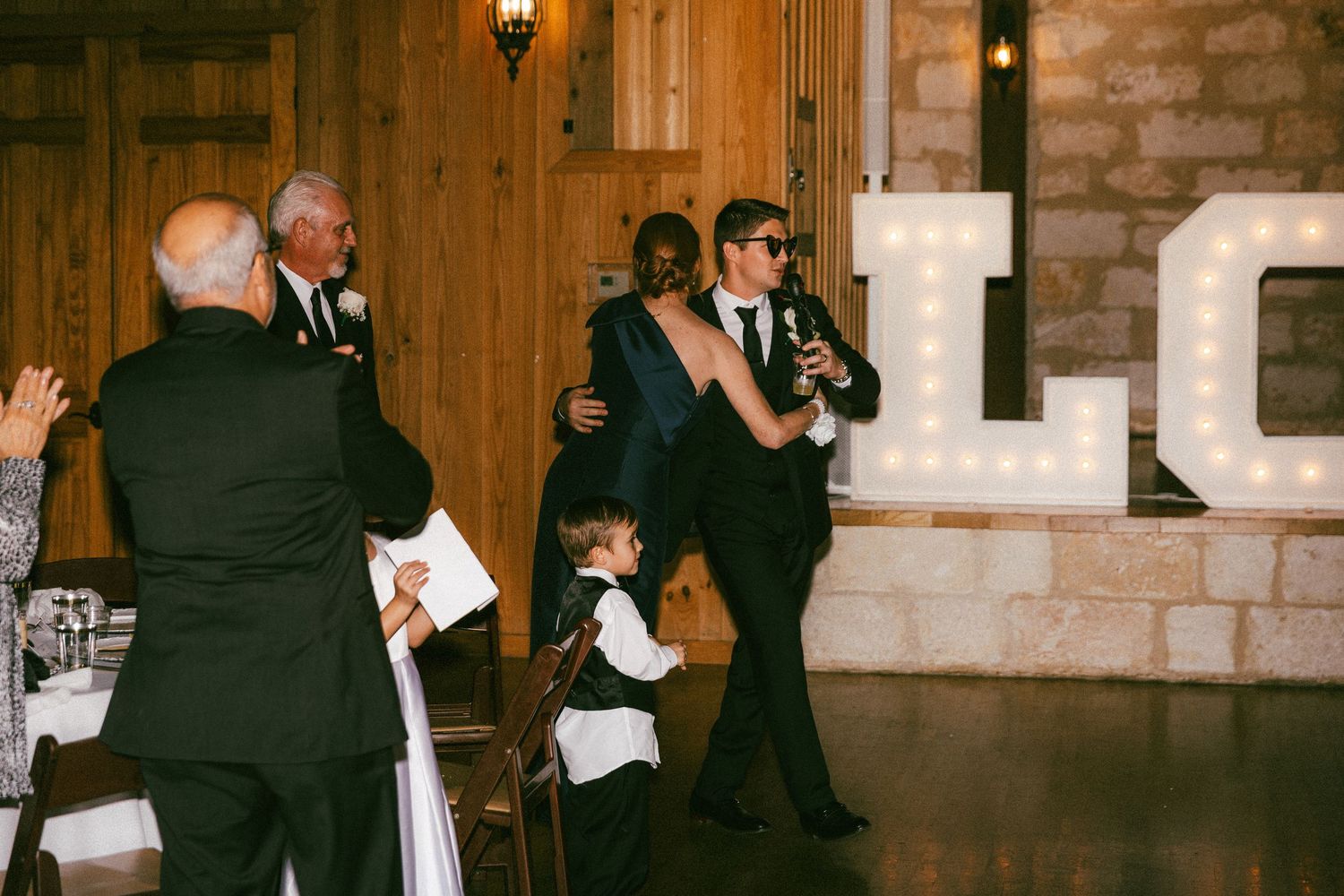 Wedding guests celebrate as the newlyweds enter the reception hall with illuminated LOVE letters.