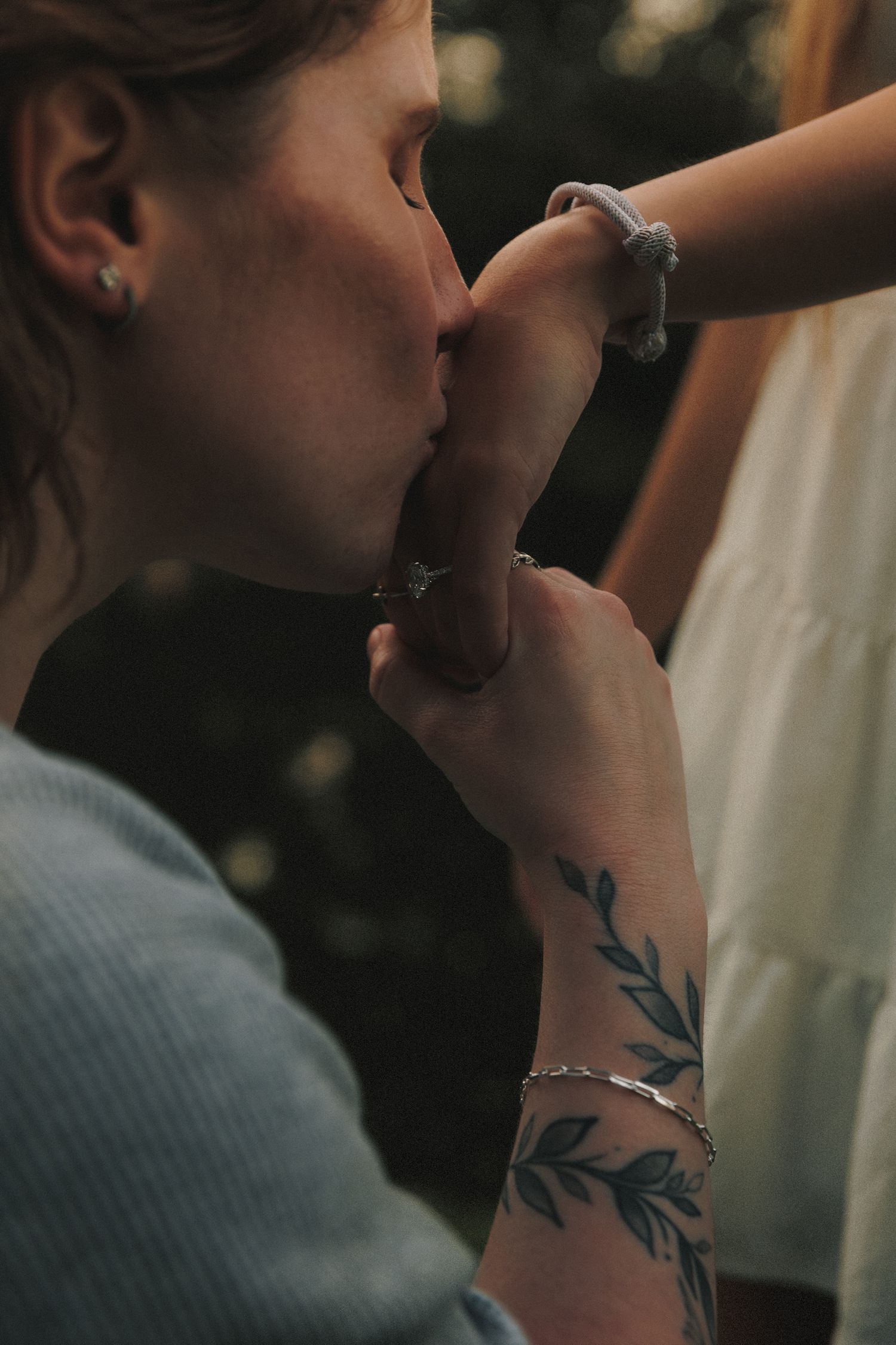 Artistic close-up photo showing hands with floral tattoo during an intimate moment.