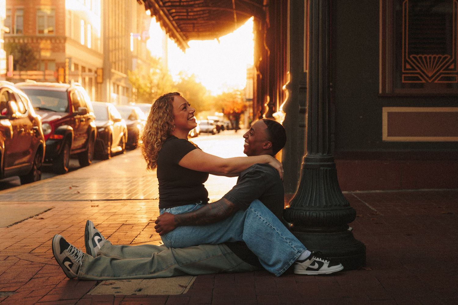 Person lying on a city sidewalk at sunset with golden light streaming through urban buildings.