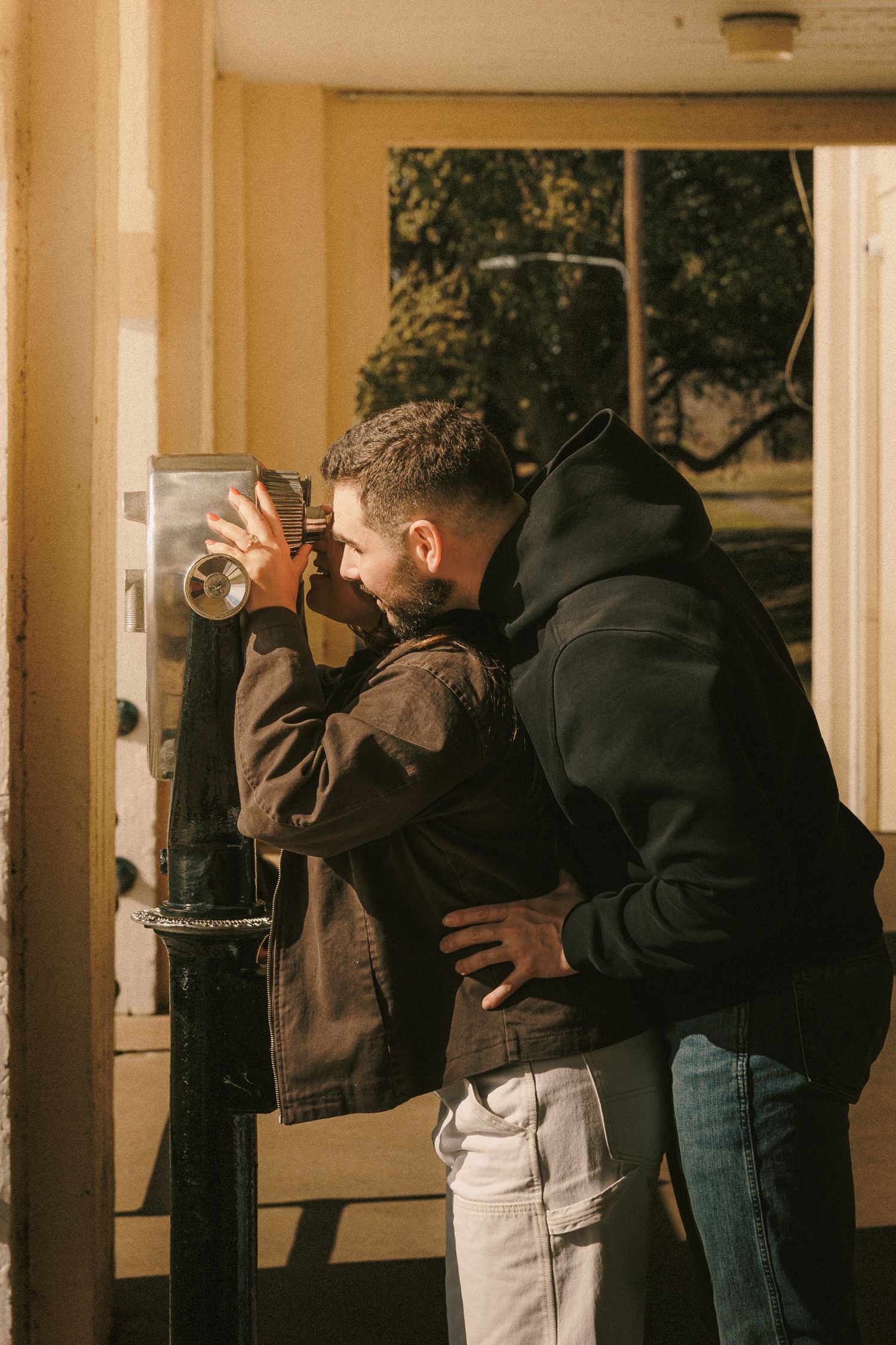 A couple embraces in a dimly lit hallway with columns casting dramatic shadows.