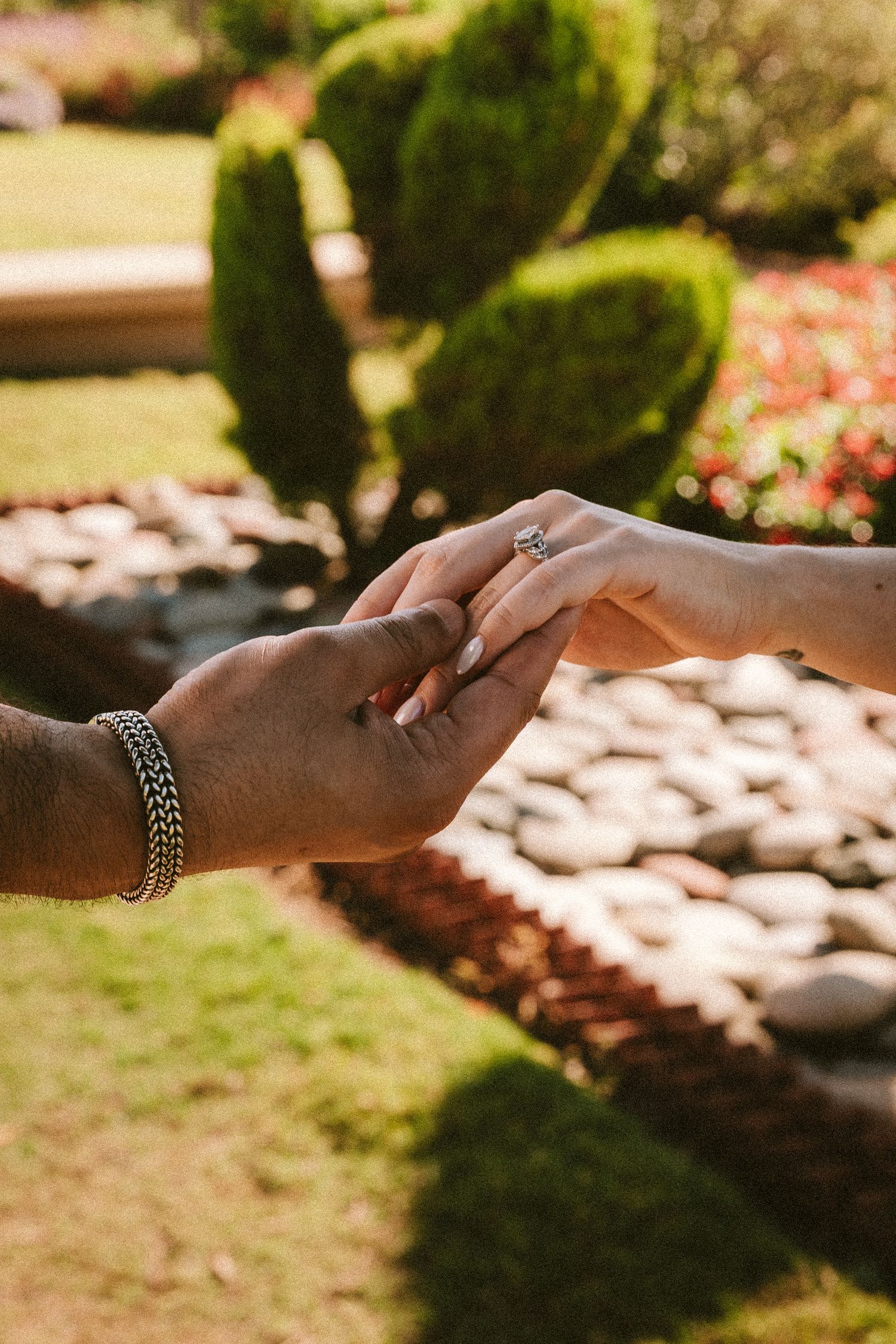 Close-up of hands with jewelry touching in warm sunlight.