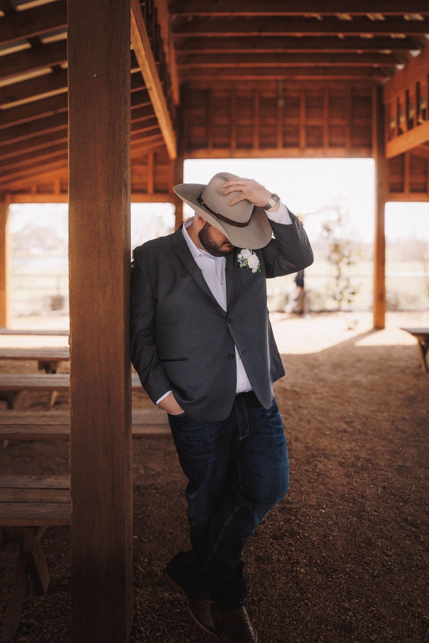 A rustic wooden barn interior with wooden beams and dirt floor makes a unique backdrop for formal attire photos.
