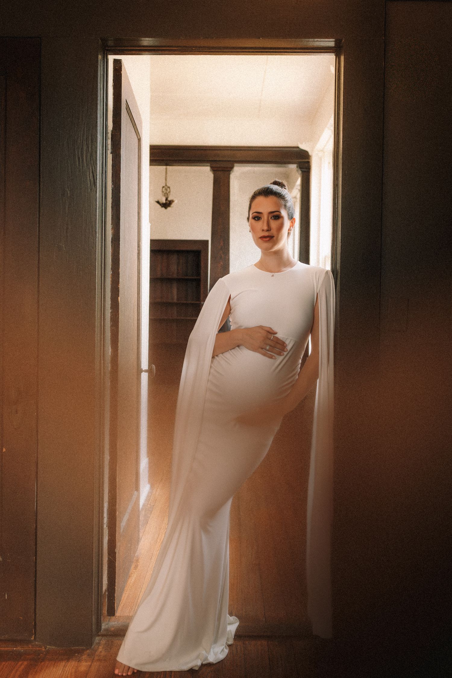 A series of artistic maternity portraits showing a figure in white against doorways with dramatic lighting.