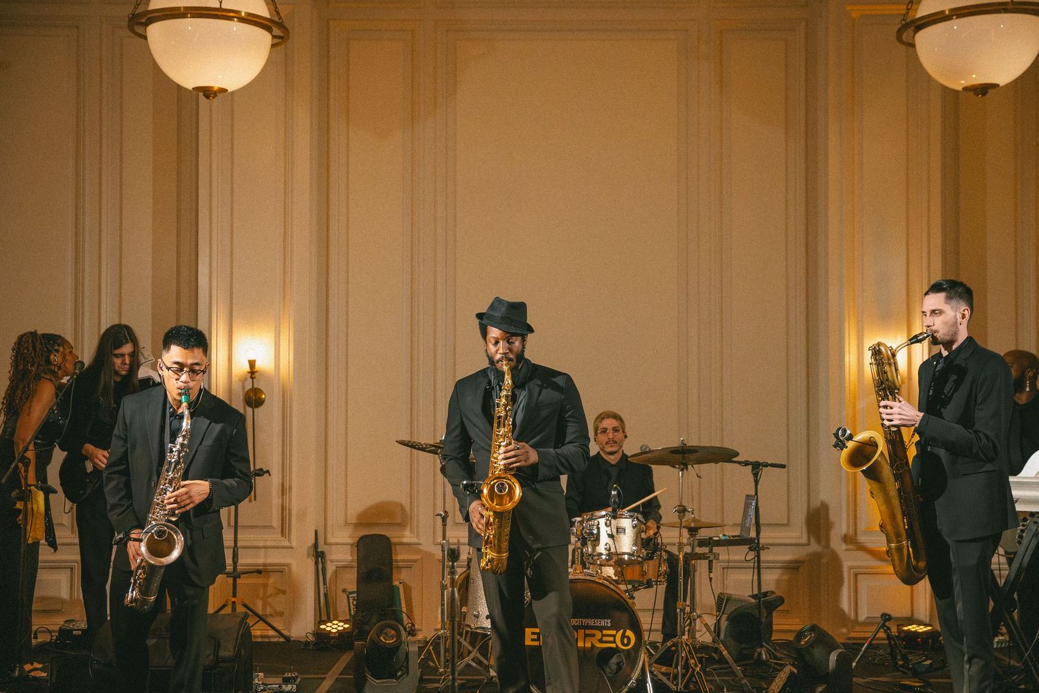 Live jazz band with saxophonists performing at an elegant wedding reception in a grand ballroom.