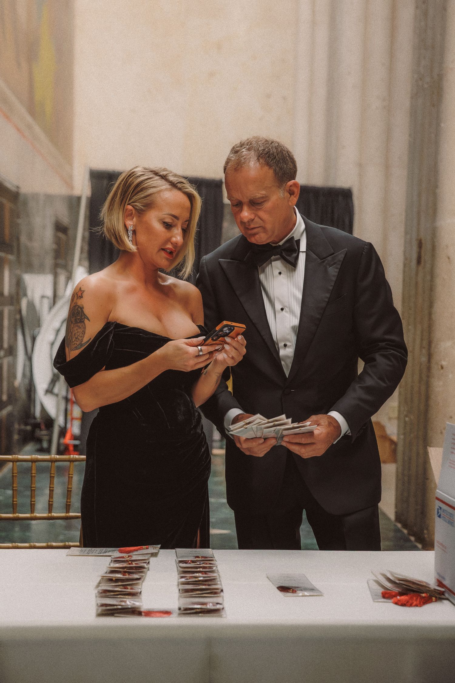 Couple in formal attire reviews items at a registration table during an upscale black-tie wedding reception event.