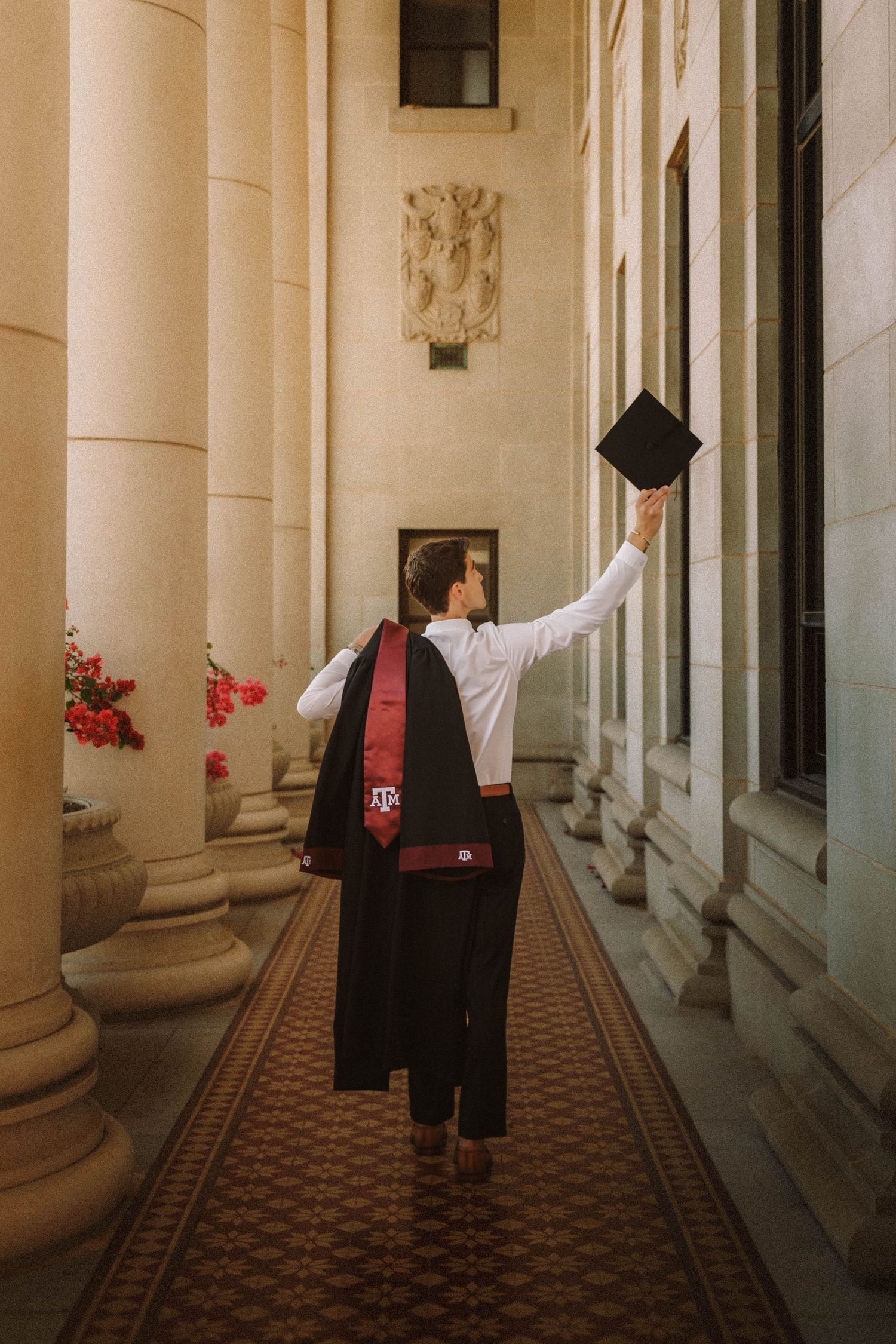 Graduation photoshoot in historic corridor showing progression of graduate throwing cap in dramatic side lighting.