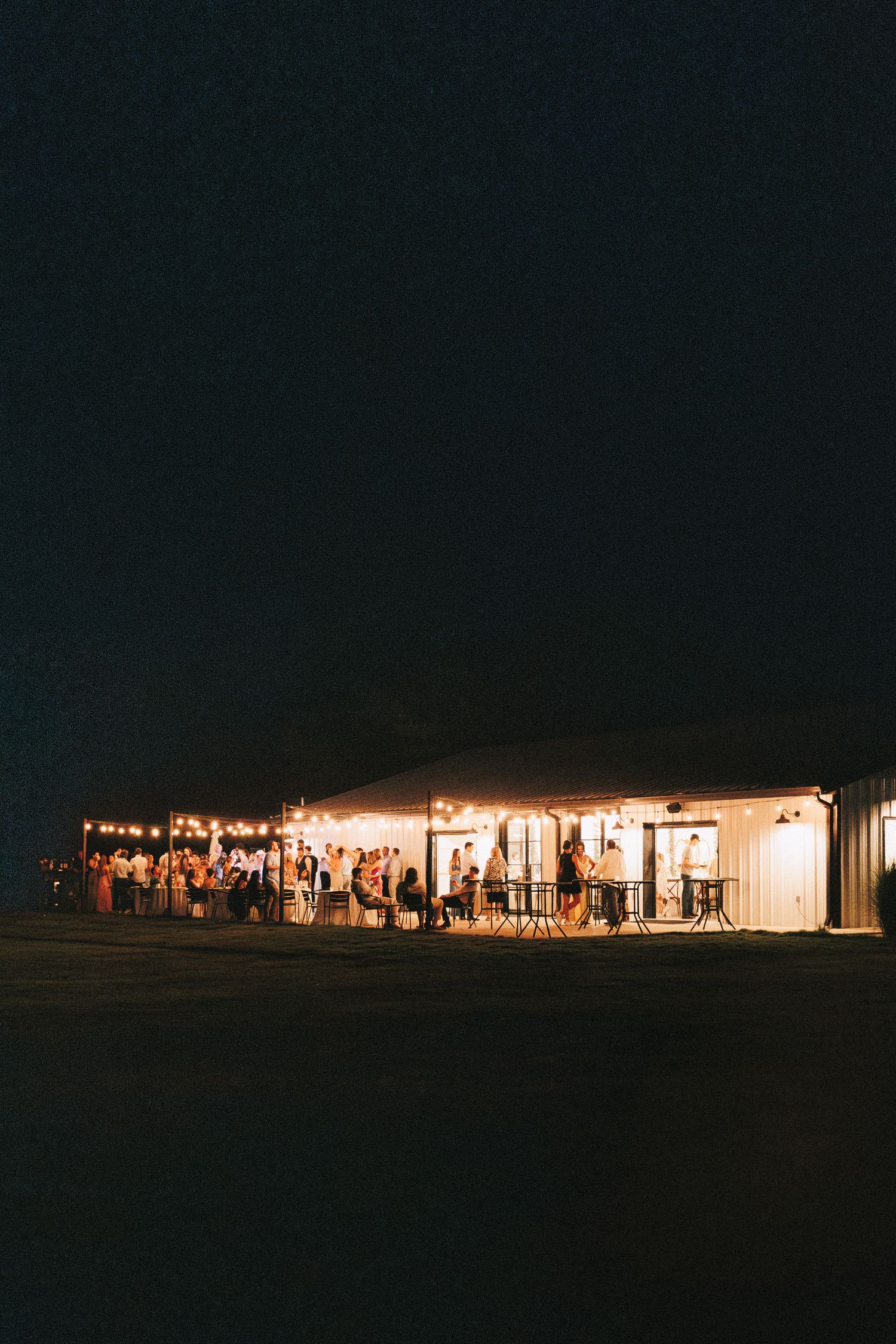 An illuminated wedding venue glows warmly against the dark night sky.