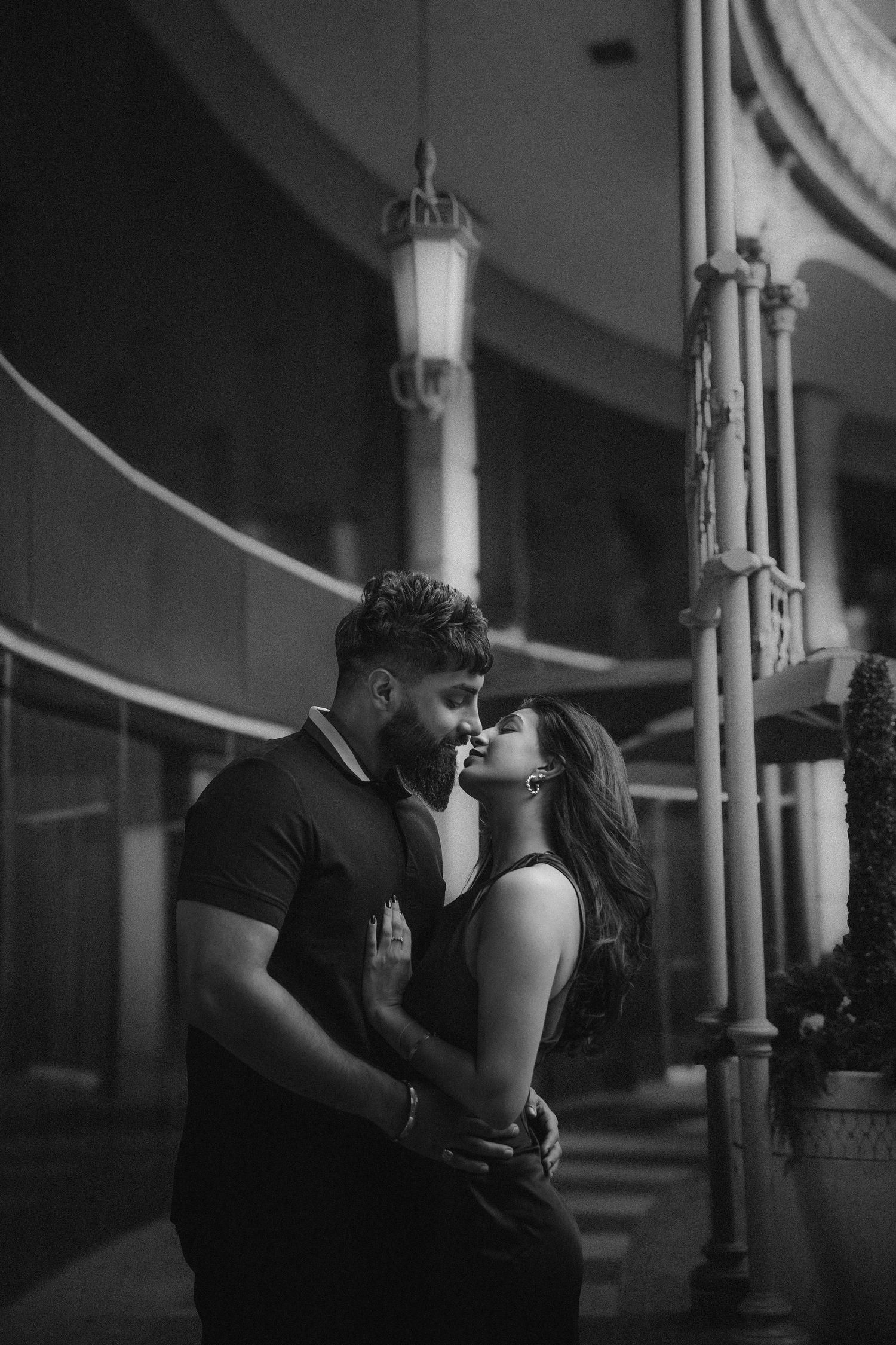 A romantic black and white photo series showing a couple in tender embraces between architectural columns.