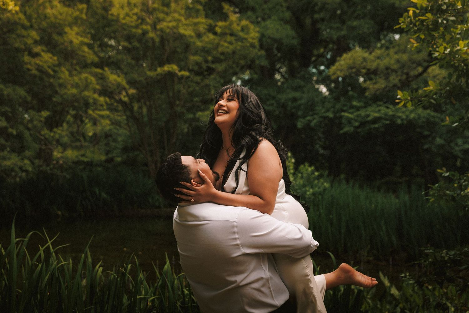A couple celebrates their wedding day outdoors in a lush garden setting at sunset.