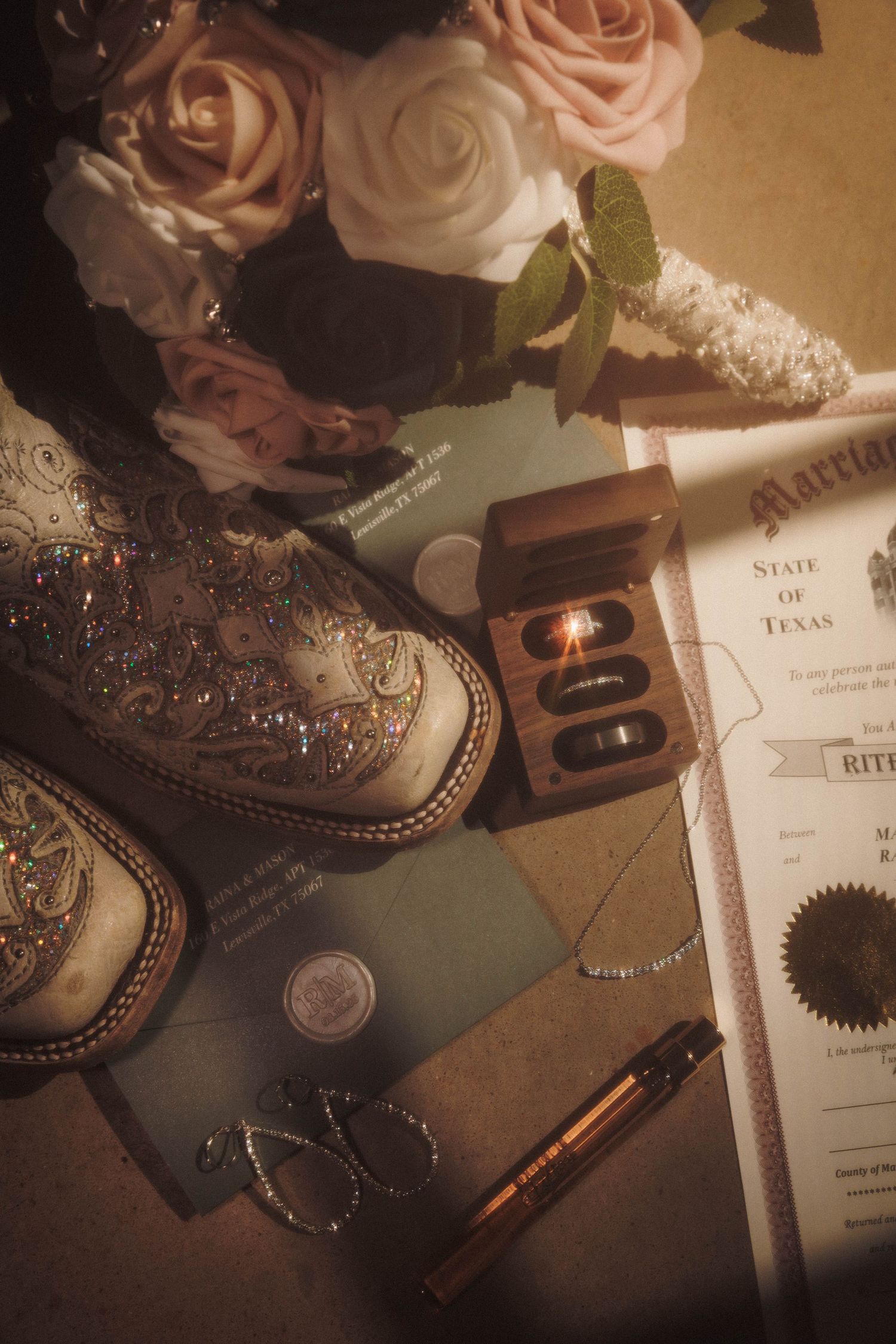 Western wedding details including embroidered boots, roses, and official documents in warm vintage lighting.