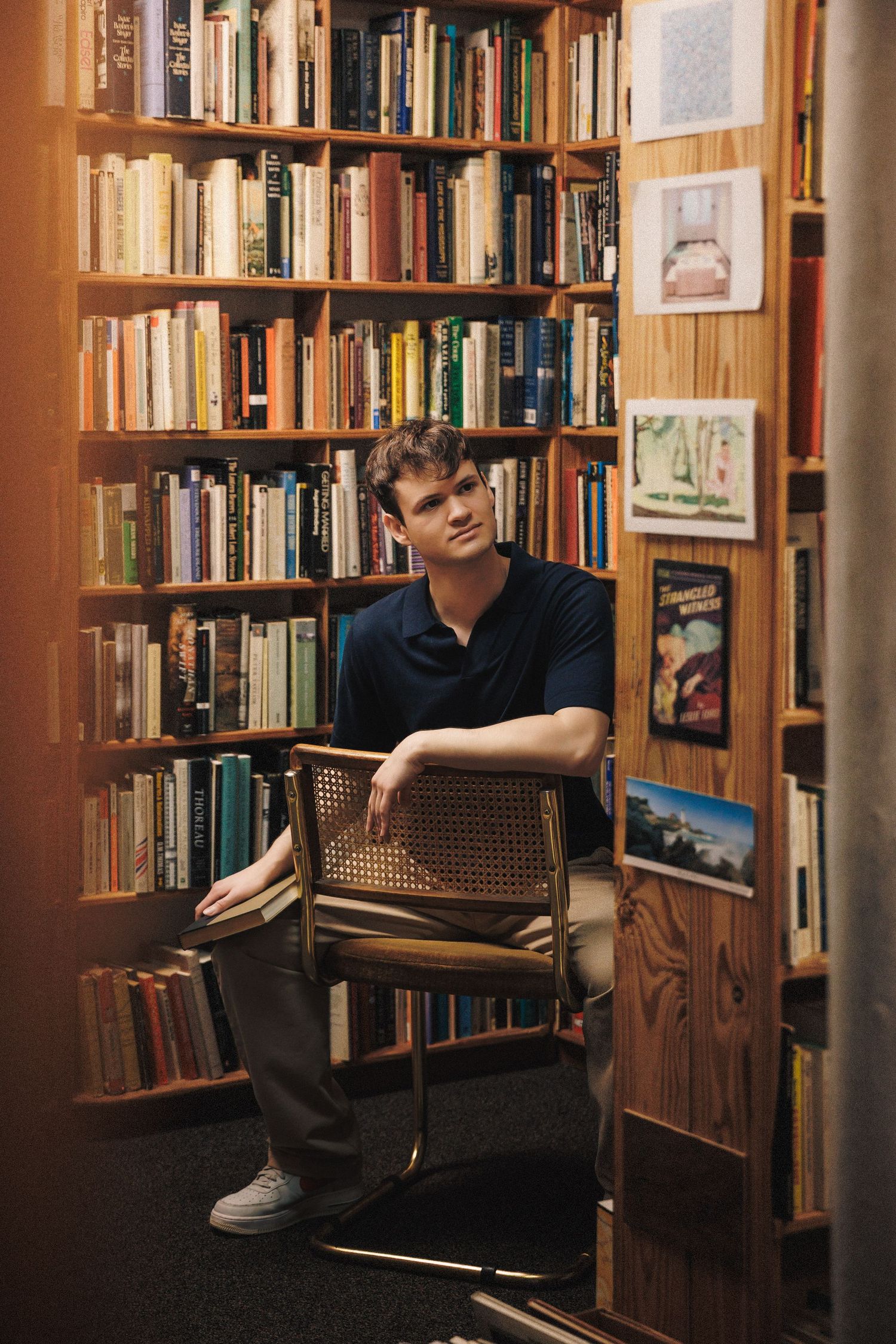 A reading nook in a library with wooden bookshelves and a vintage cane chair creates a cozy atmosphere.