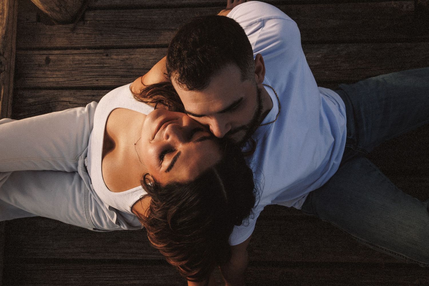Romantic couple embracing on a wooden dock during golden hour.
