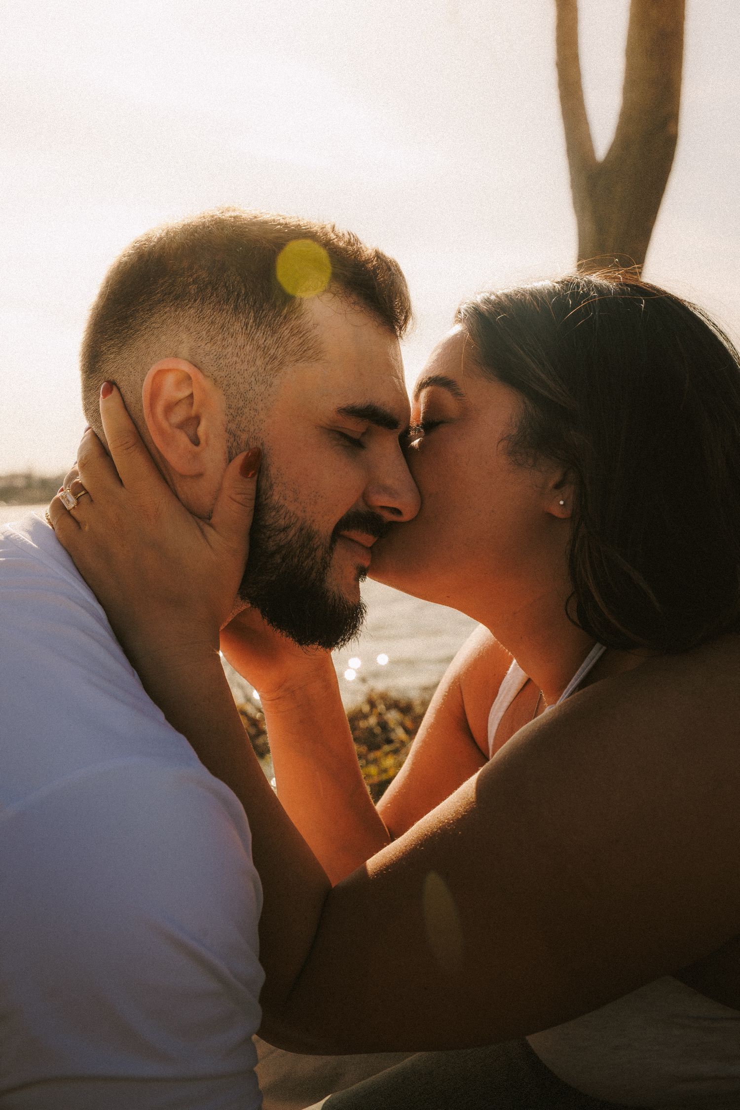 A romantic couple sharing an intimate moment in warm sunlight with a lens flare effect.
