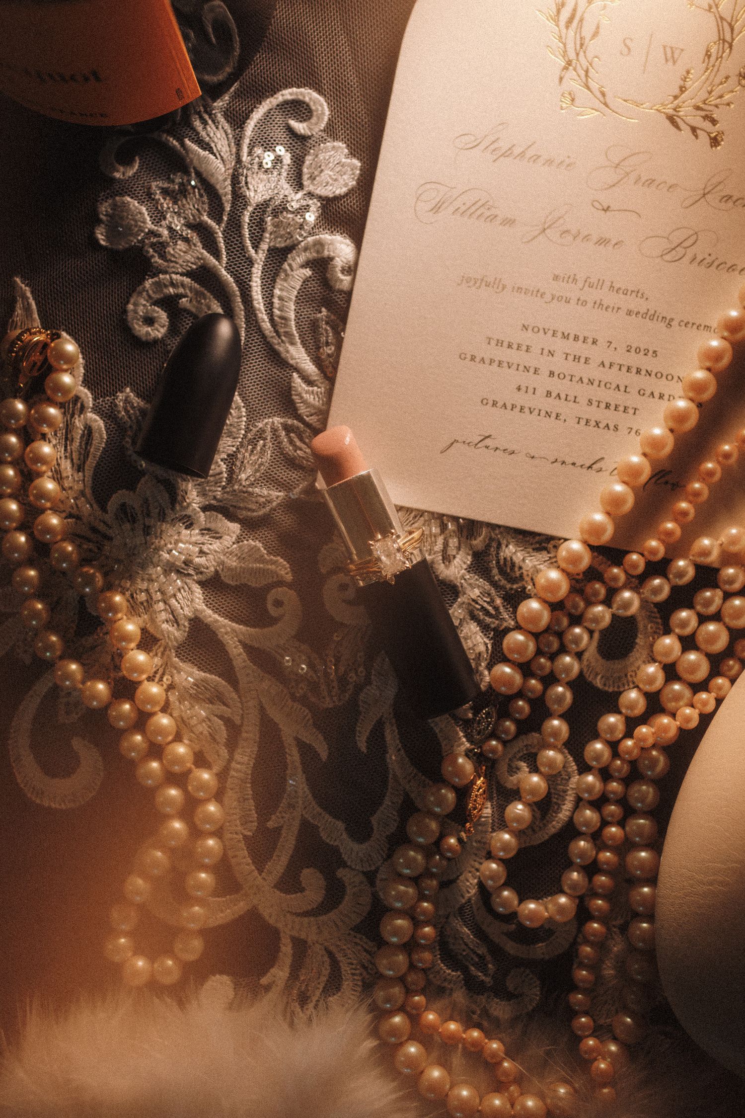 Wedding flat lay with pearl necklaces, nude lipstick, lace fabric, and elegant invitation for a Texas ceremony.